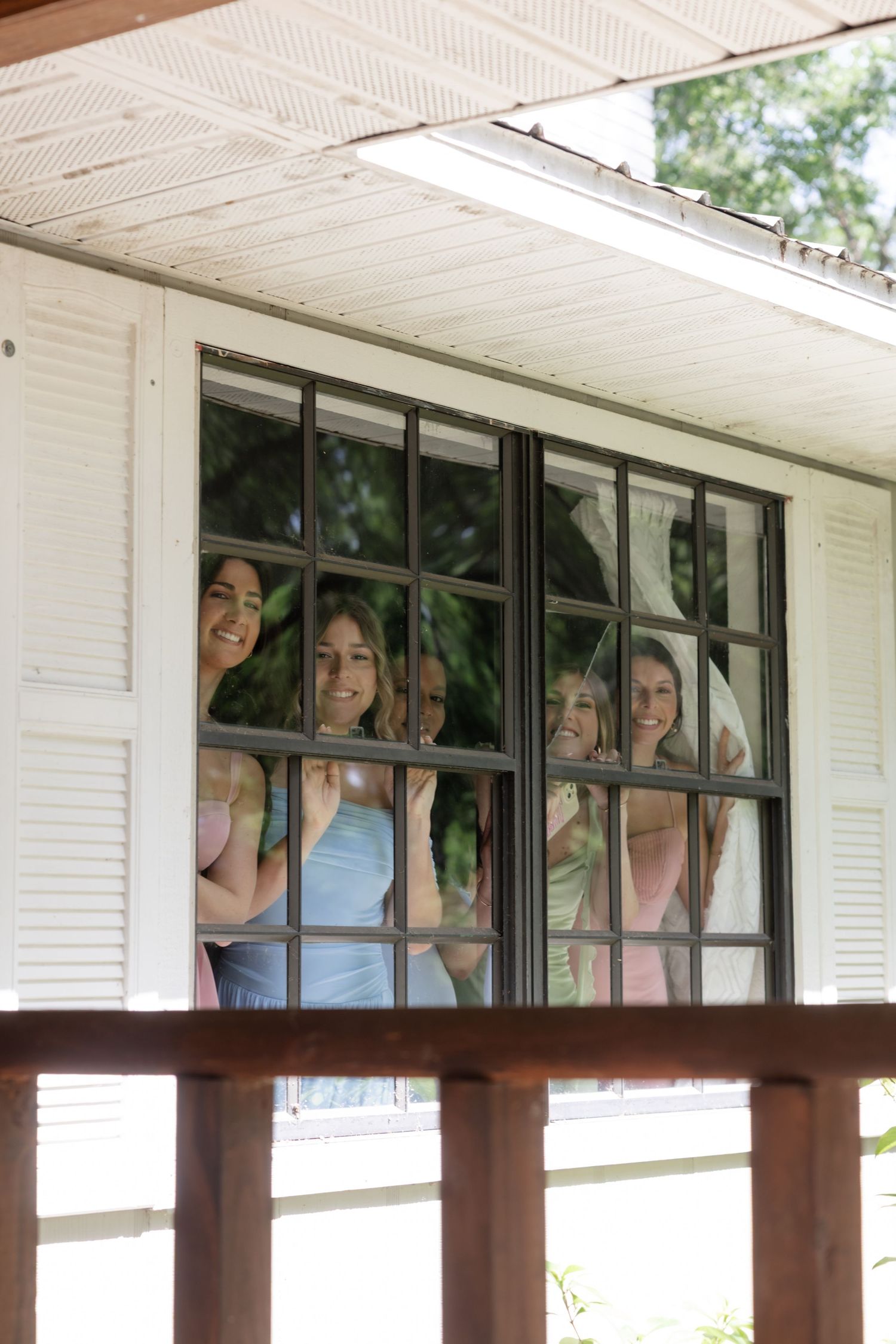People peek through large windows of a white building with playful expressions.