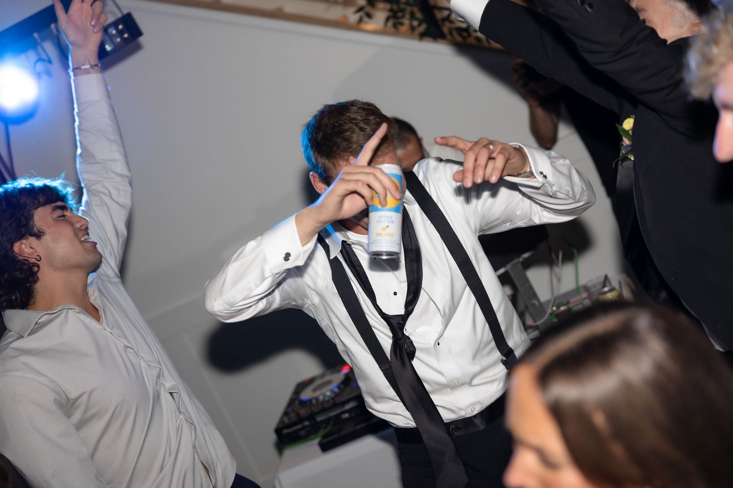 Guest dances enthusiastically with suspenders at reception party.