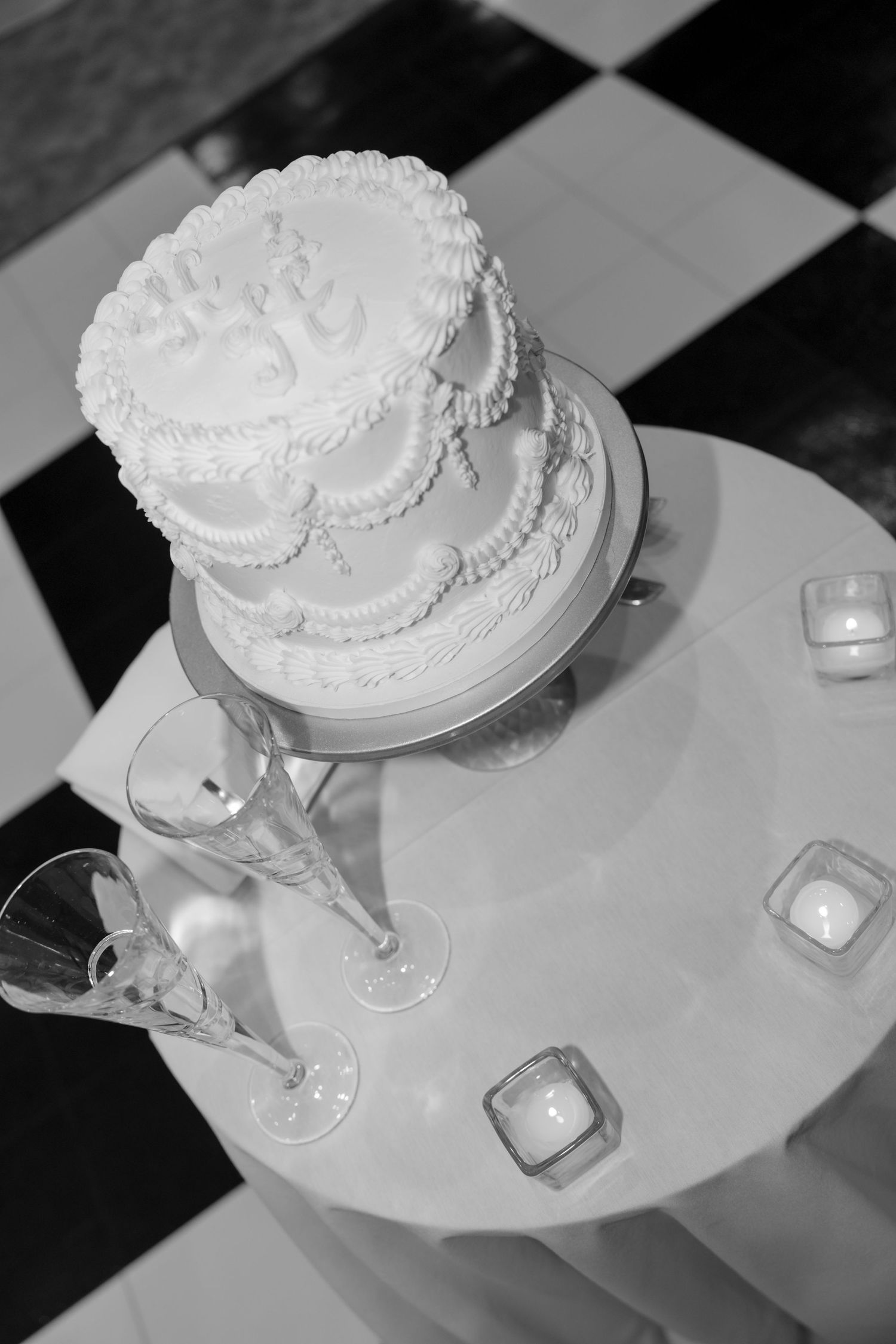 Black and white photos of elegant white wedding cakes displayed on stands.
