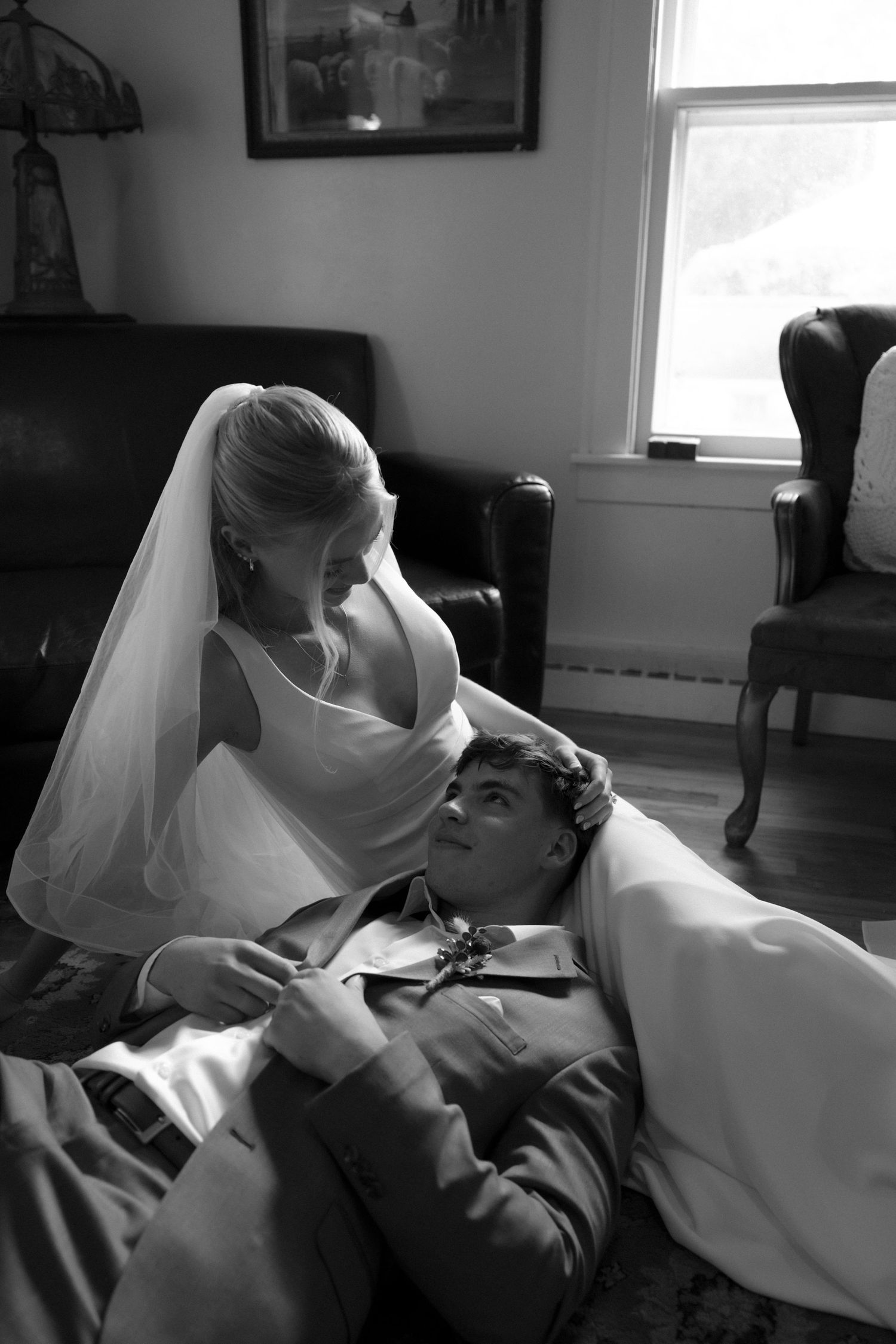 Couple embracing on a leather couch in an indoor setting with natural window light.