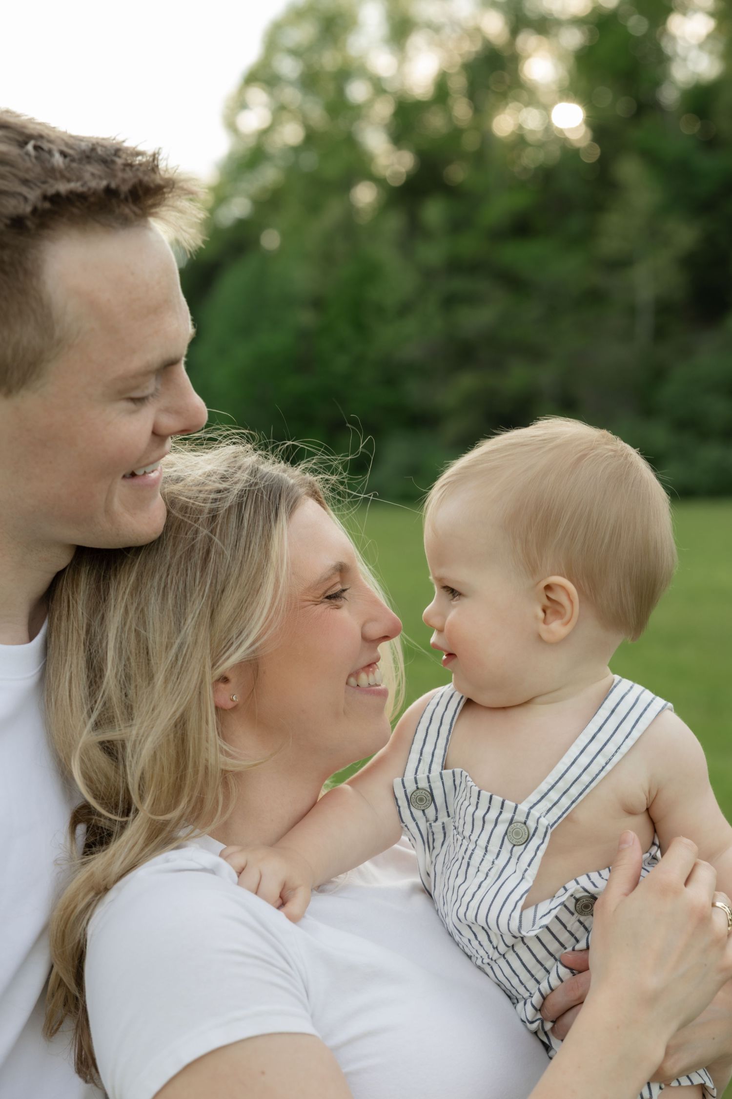 A family shares loving moments together outdoors in matching white outfits.