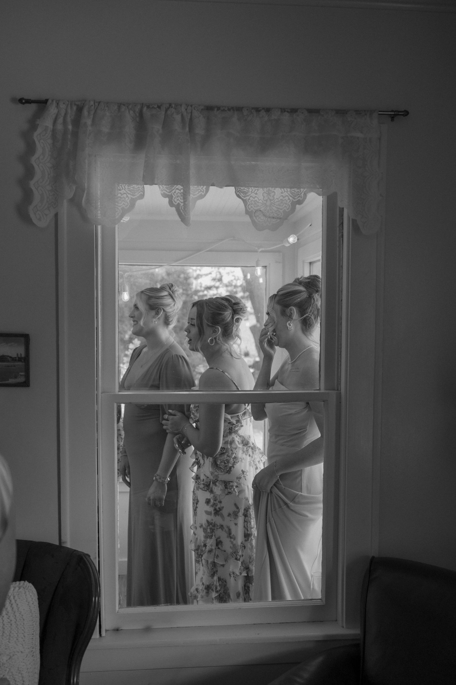 Group gathered by a window in formal attire at an indoor event.