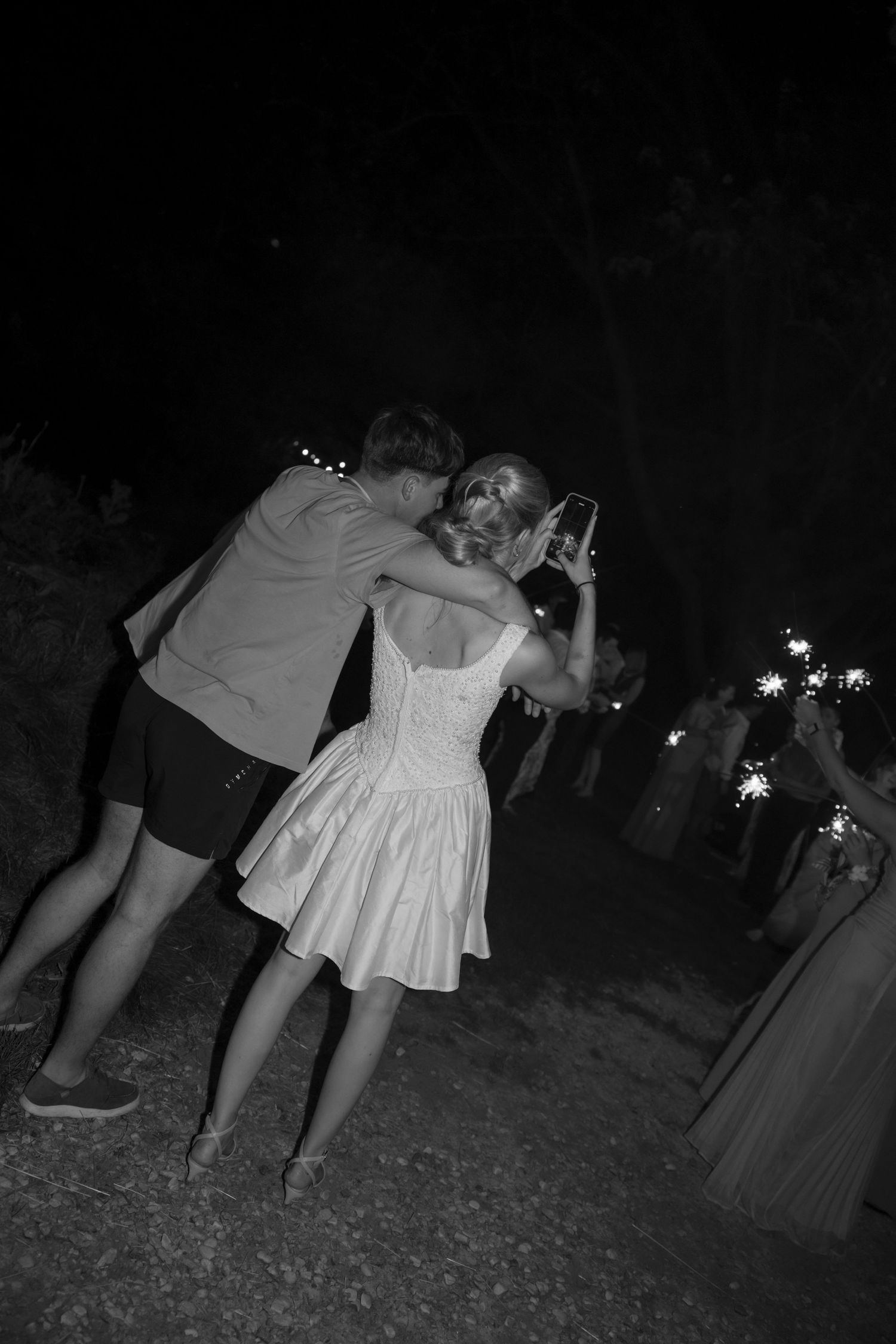 Guests hold sparklers while dancing at an outdoor nighttime celebration.