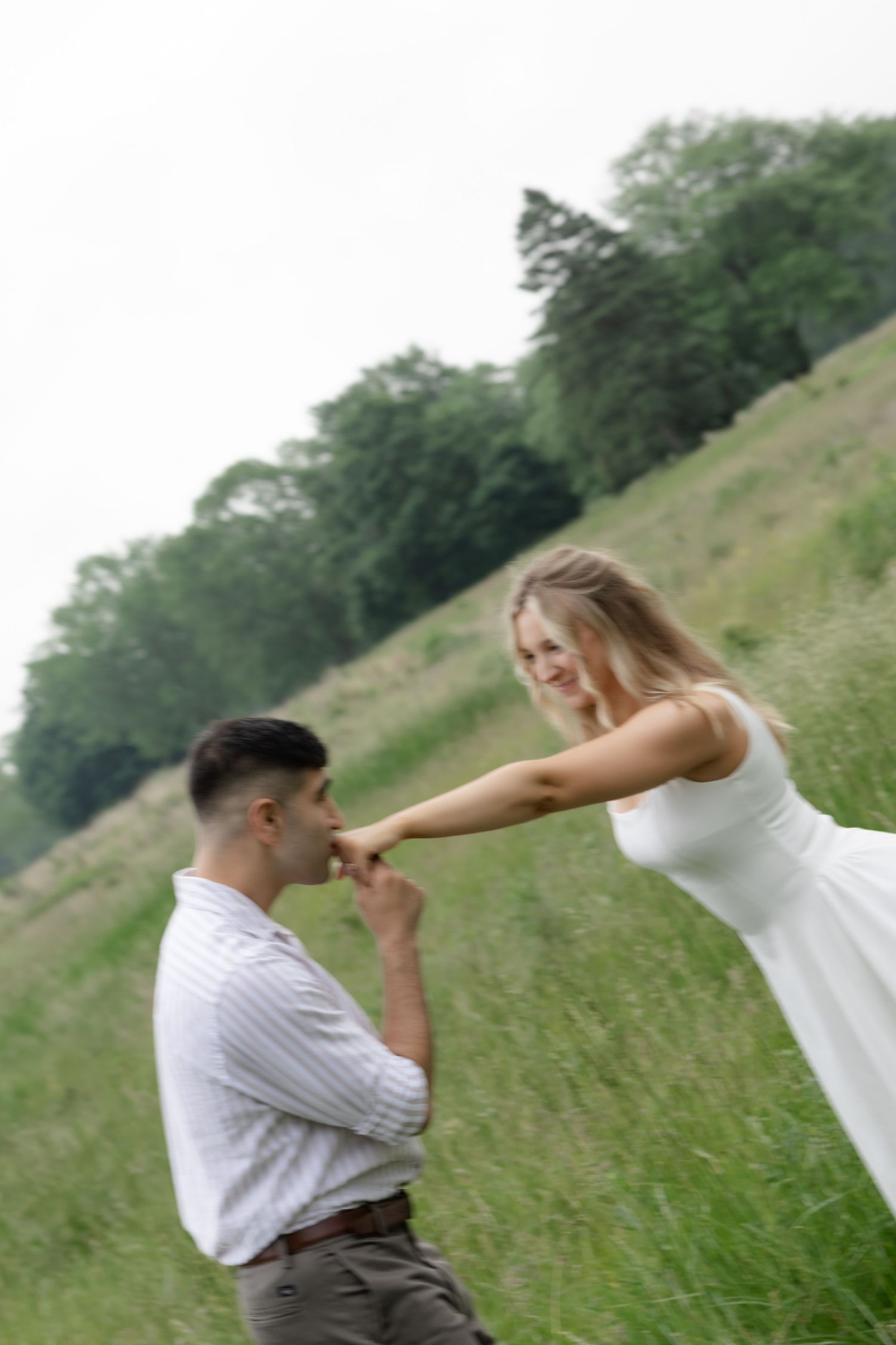 A couple dances and twirls together in a grassy field.