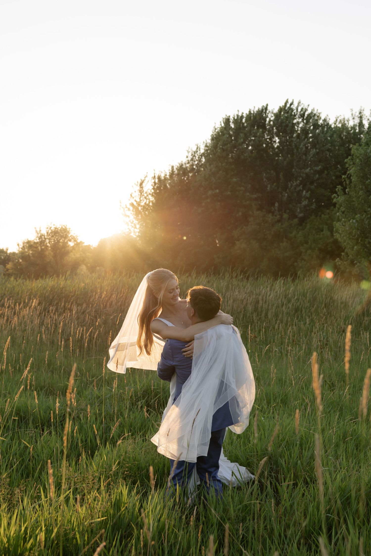 Romantic couple dancing in a summer field with golden sunlight behind them.
