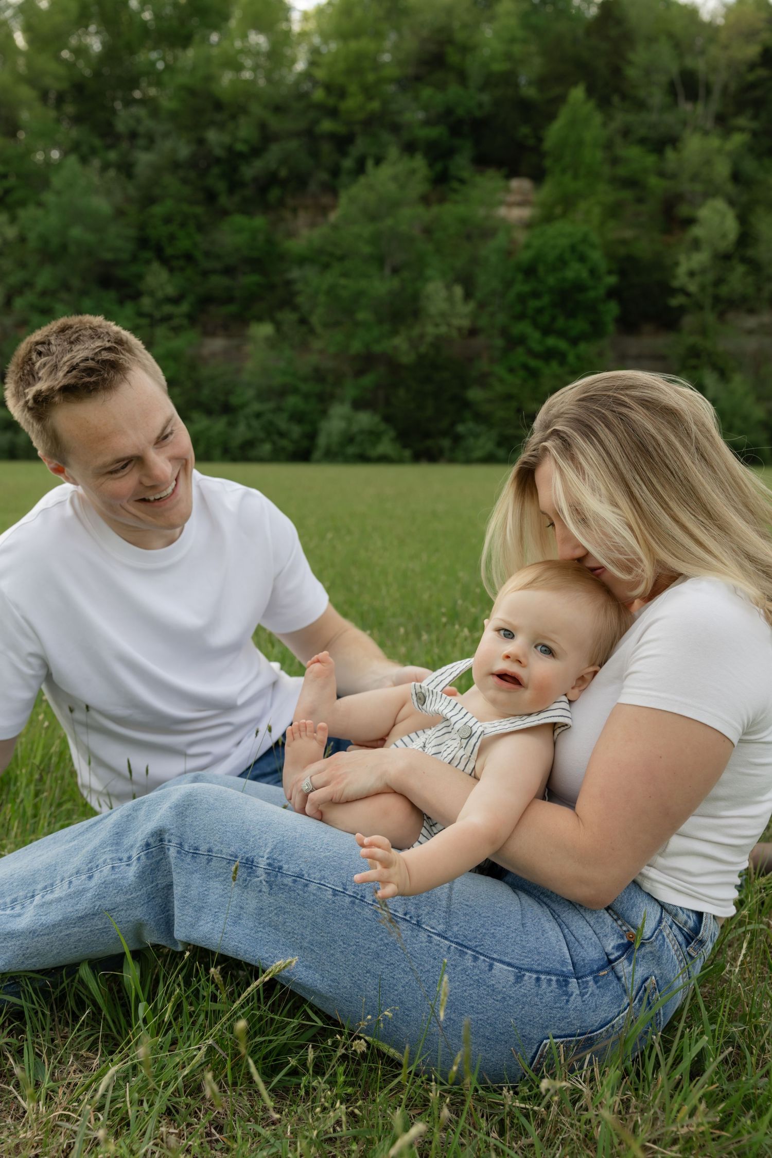 Family lying on grass enjoying a relaxed outdoor moment together.