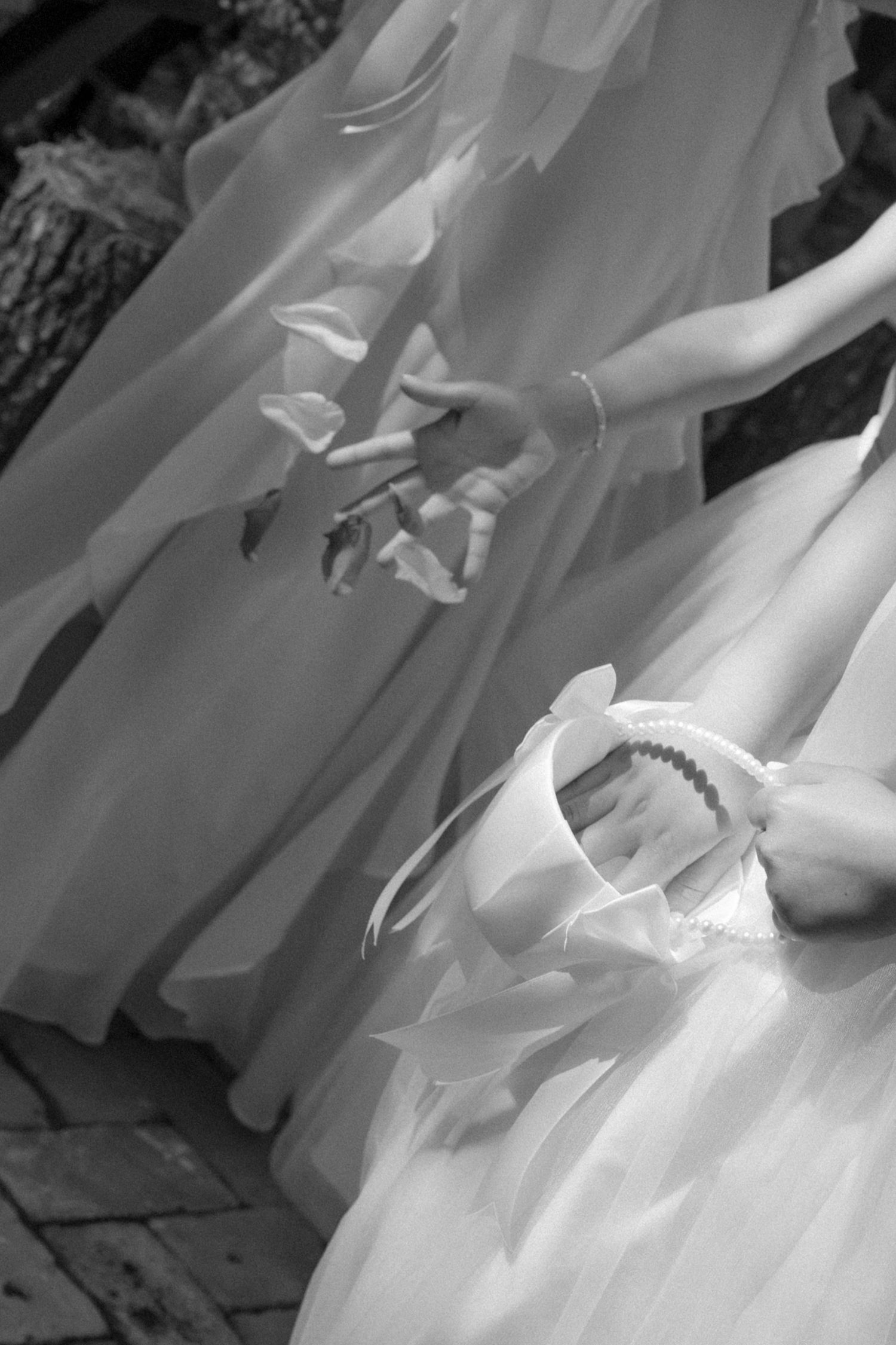 Black and white detail shot of flowing wedding dress fabric and delicate lace details.