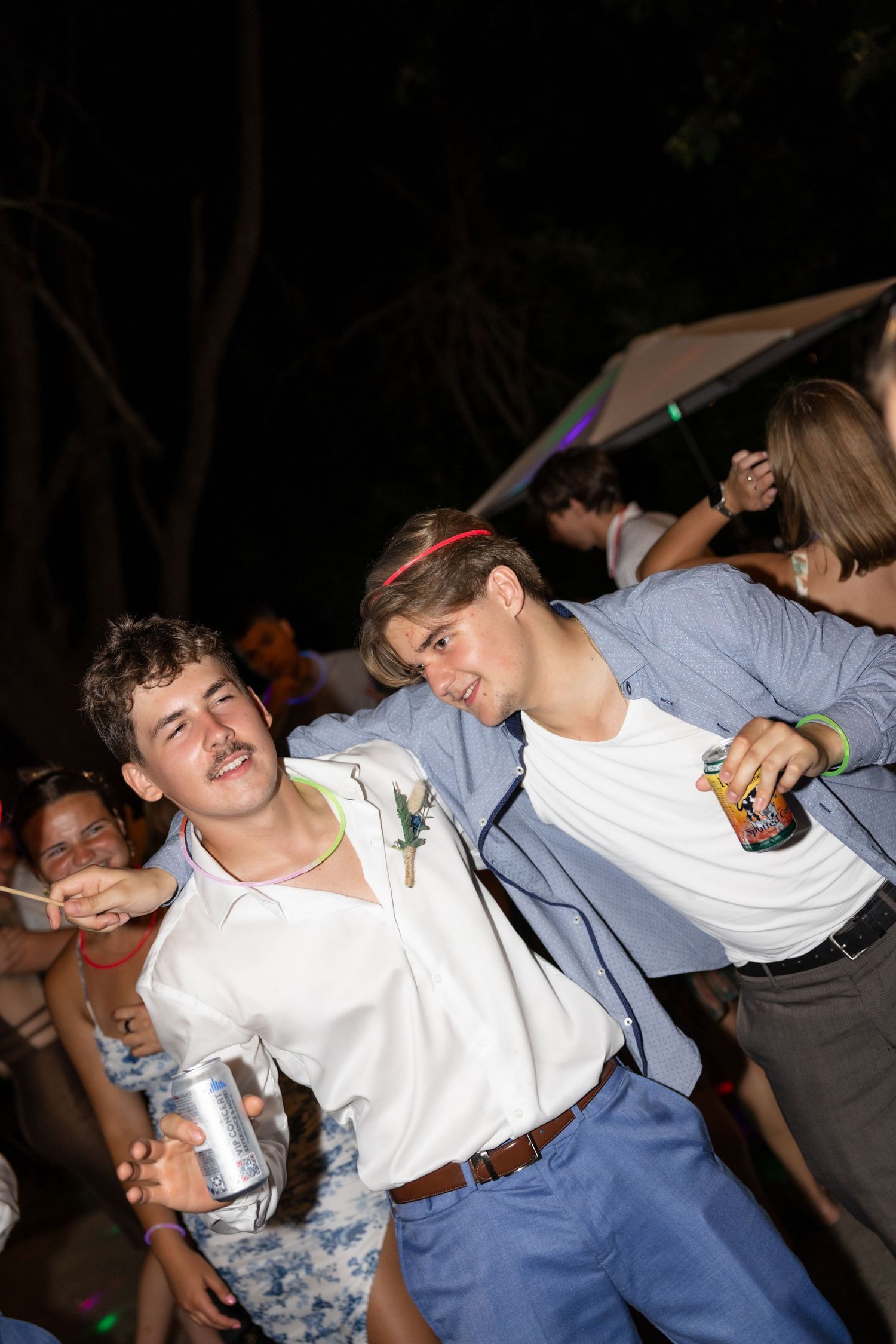 People dancing energetically at a nighttime party under string lights.