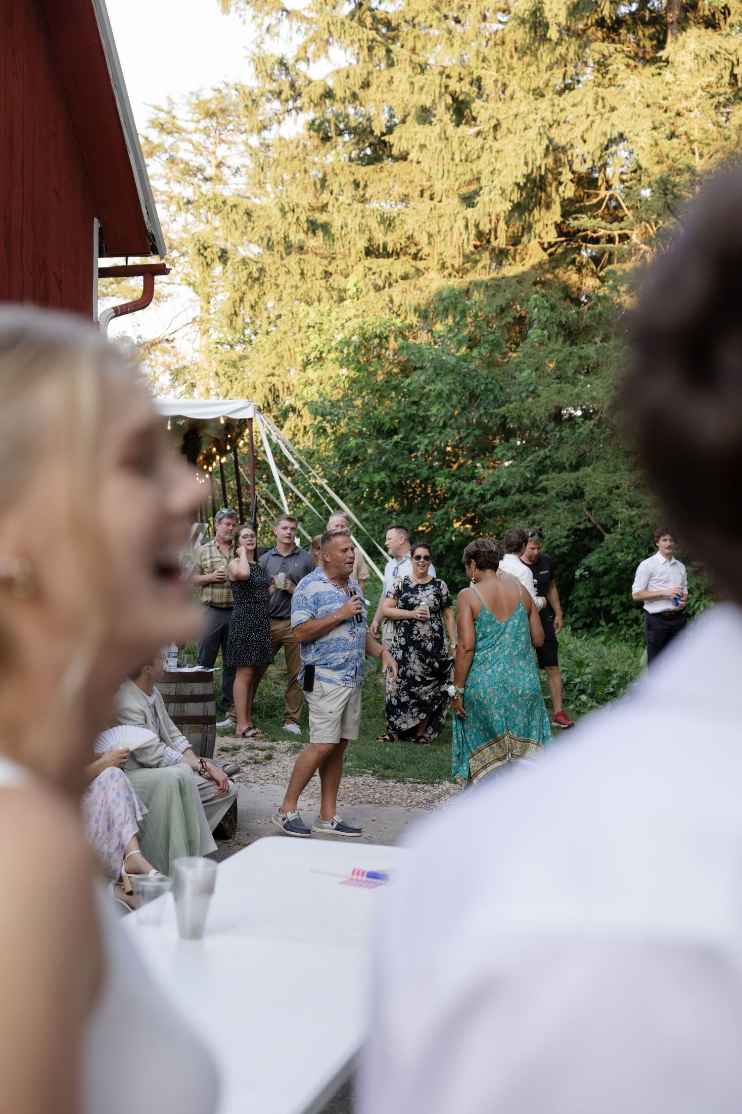 Wedding reception guests enjoying outdoor dancing at sunset near a red barn.