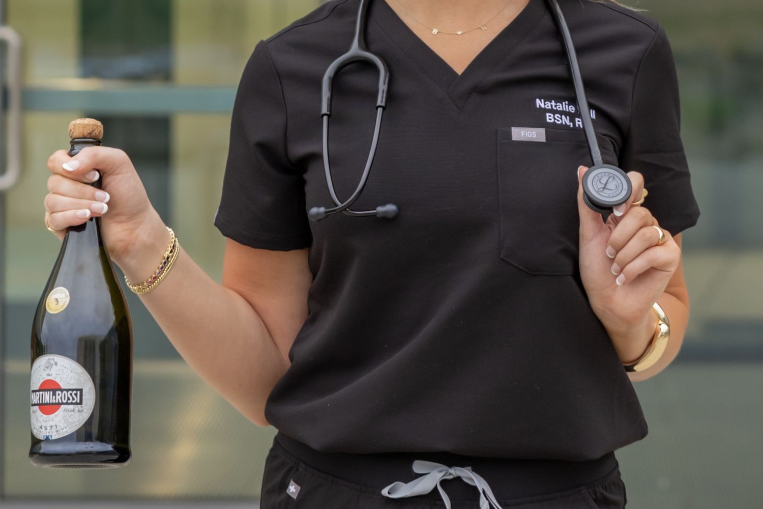 A close-up shot shows someone wearing black clothing holding a metal stethoscope against a blurred background.