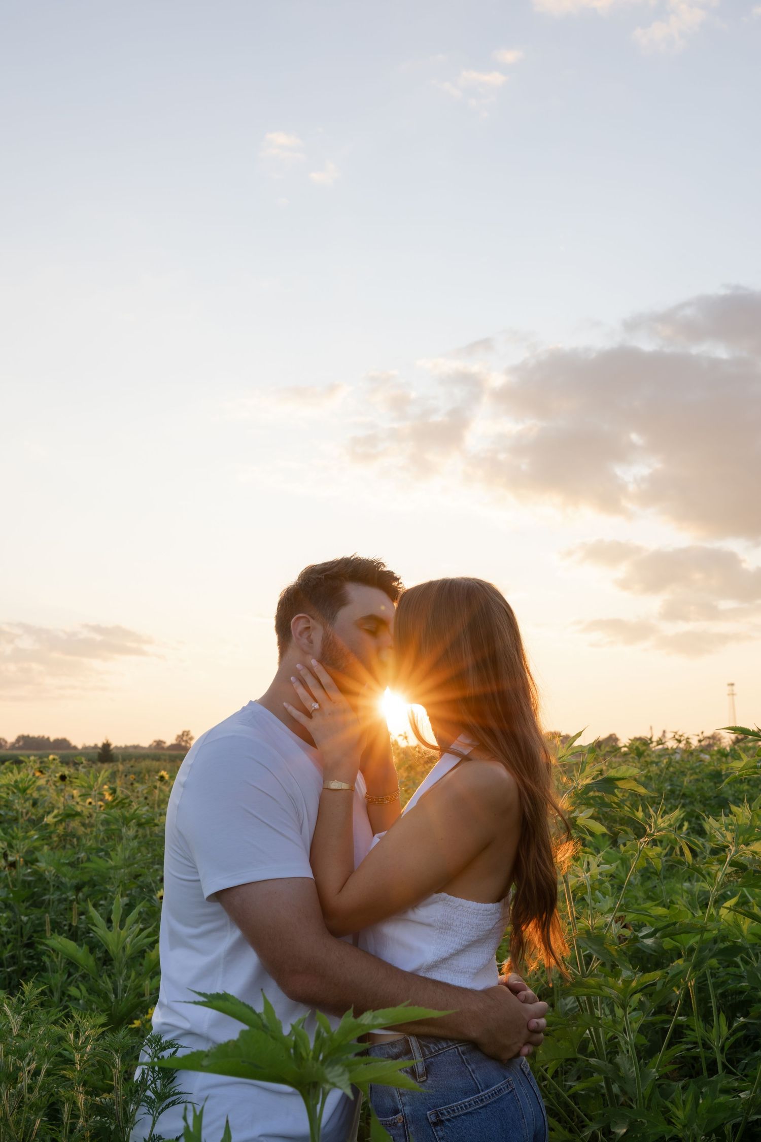 A romantic sunset moment captured in a field with golden light streaming through the trees.