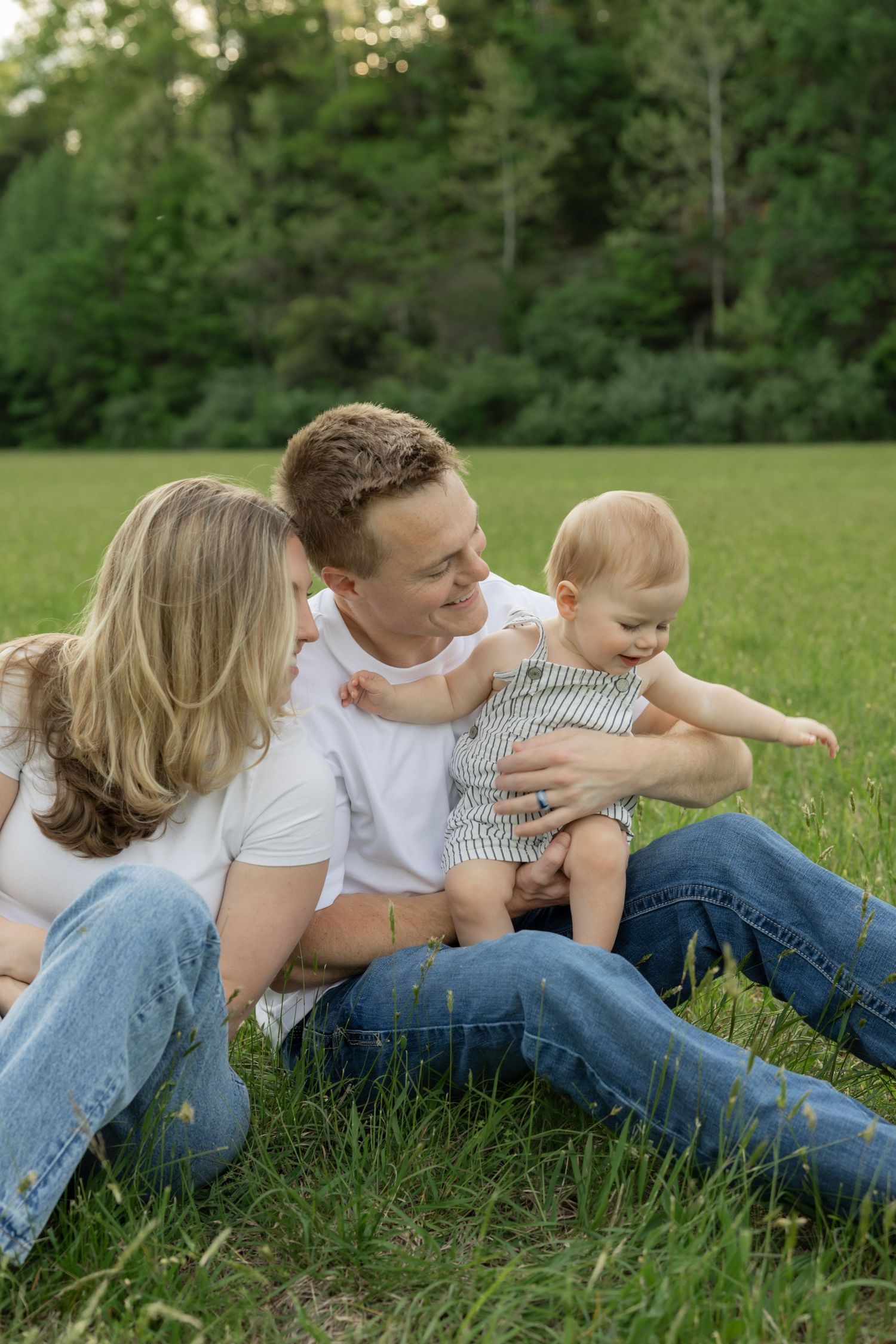 A family lying together on green grass sharing playful moments.