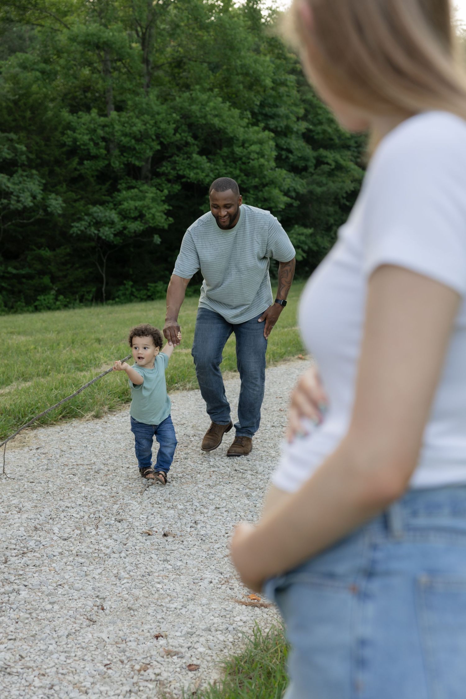 Family walking together on a gravel path surrounded by trees.