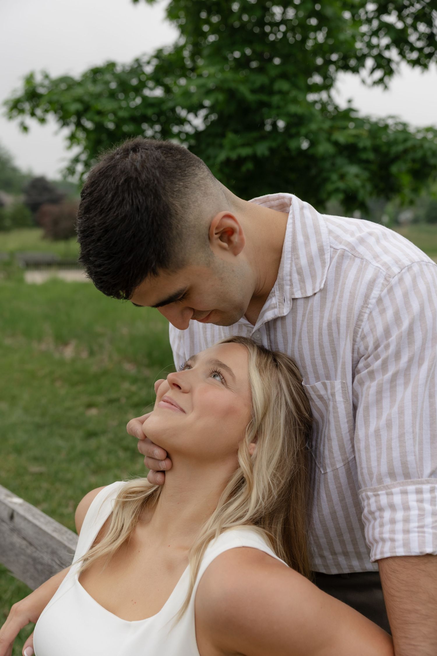 A romantic moment captured between a couple in a grassy outdoor setting.