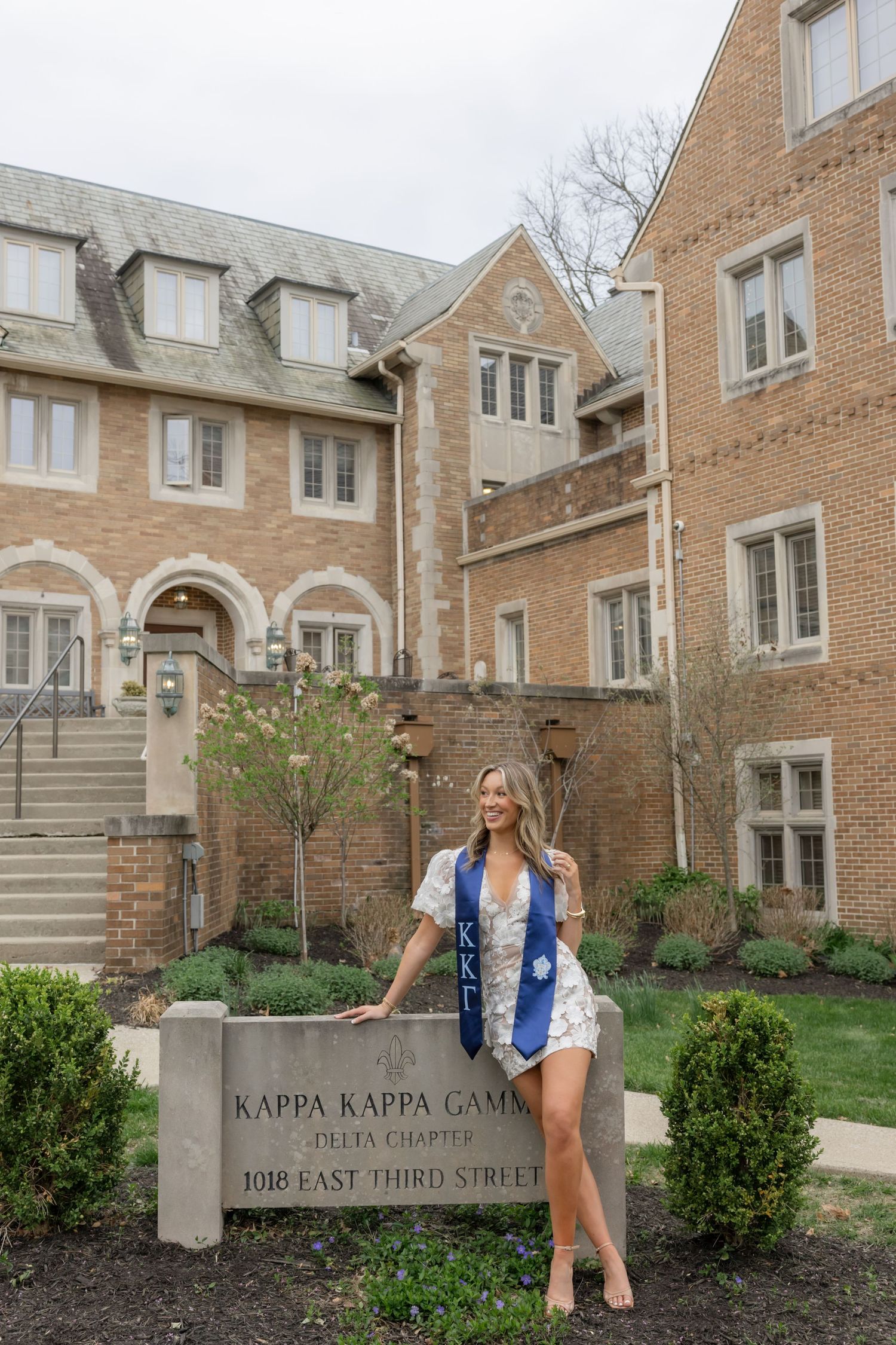 Exterior view of Kappa Kappa Gamma sorority house with person posing by entrance sign.