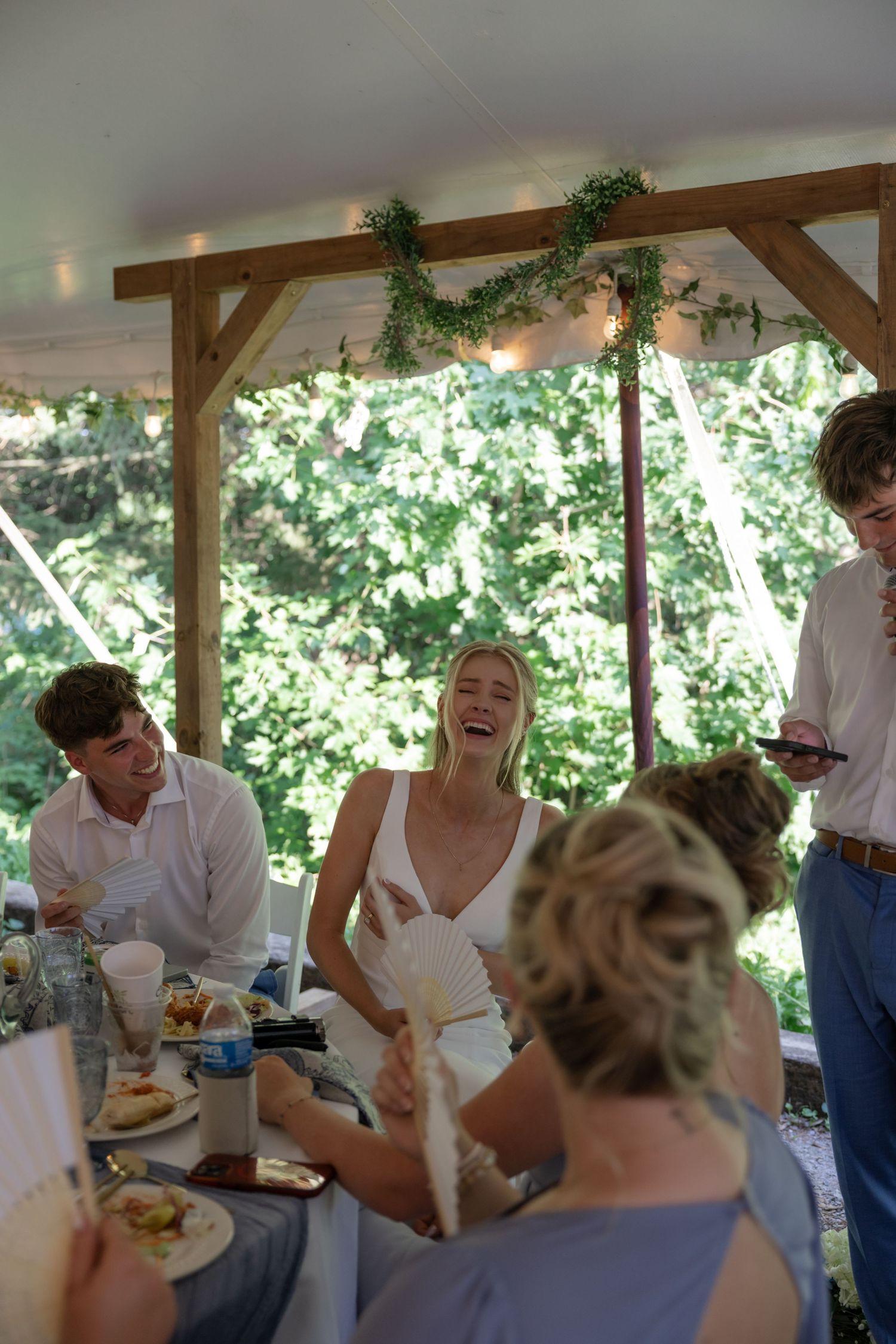 Joyful moments captured during wedding reception toasts under a covered venue.