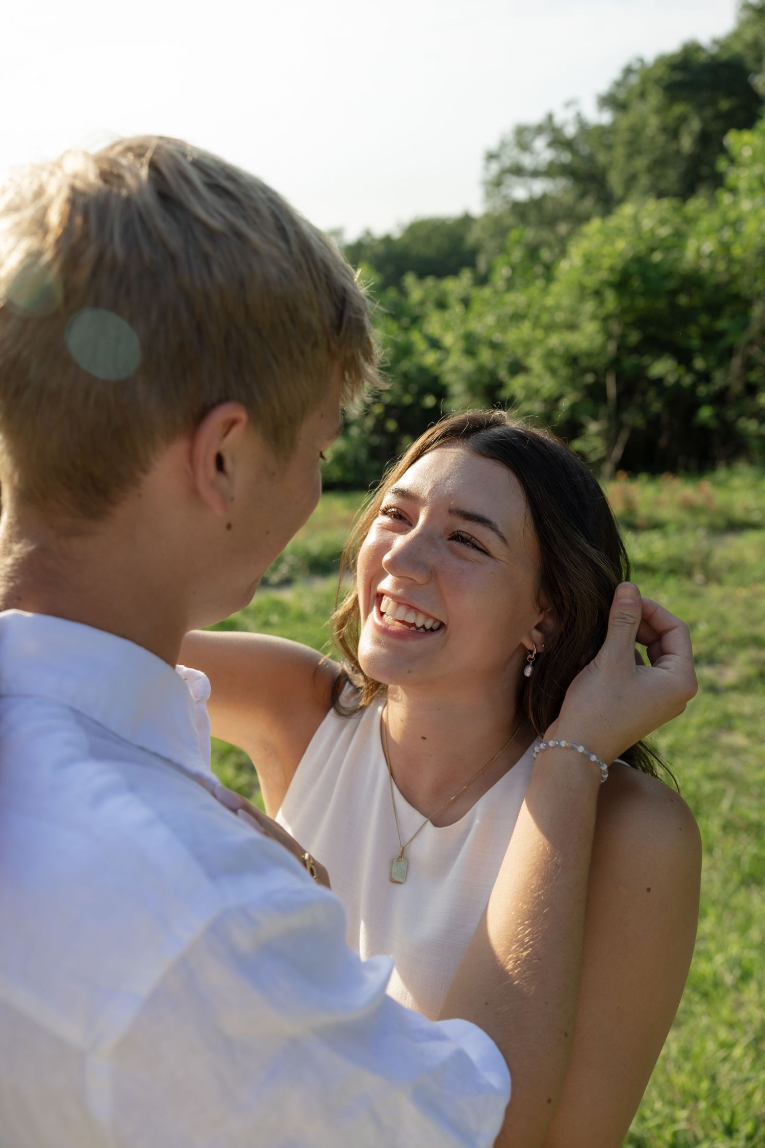 A romantic sequence captured in a sun-drenched field with rolling hills in the background.