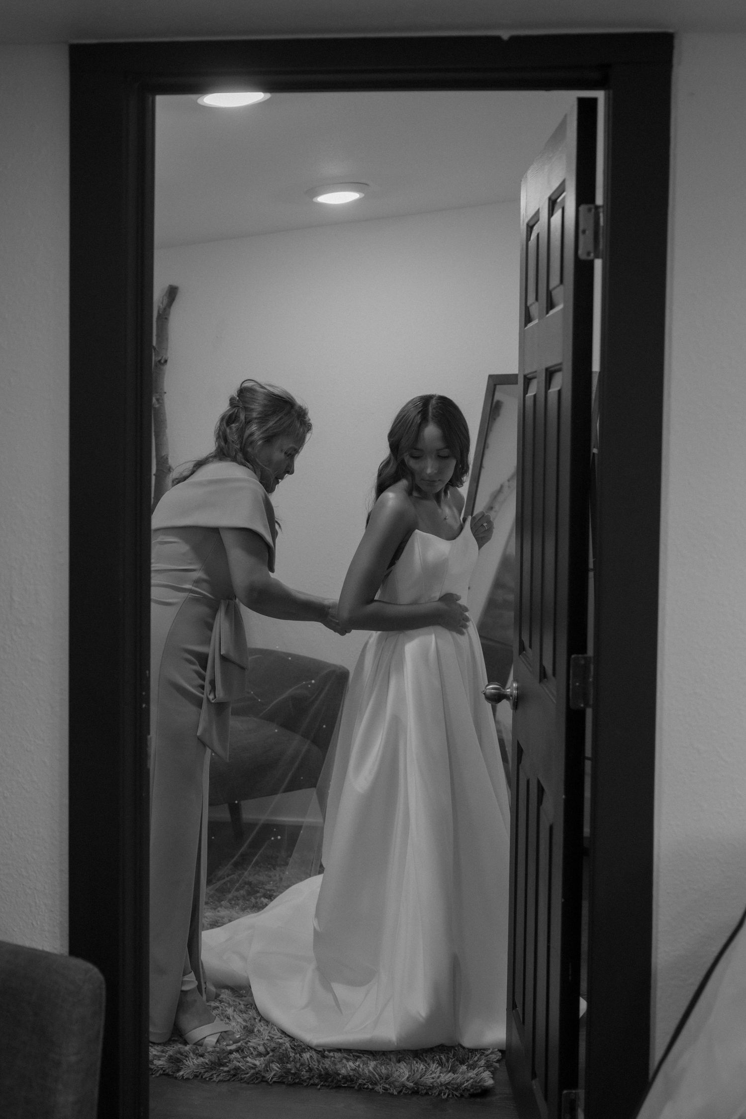 Black and white mirror reflection of dress preparation in hallway.
