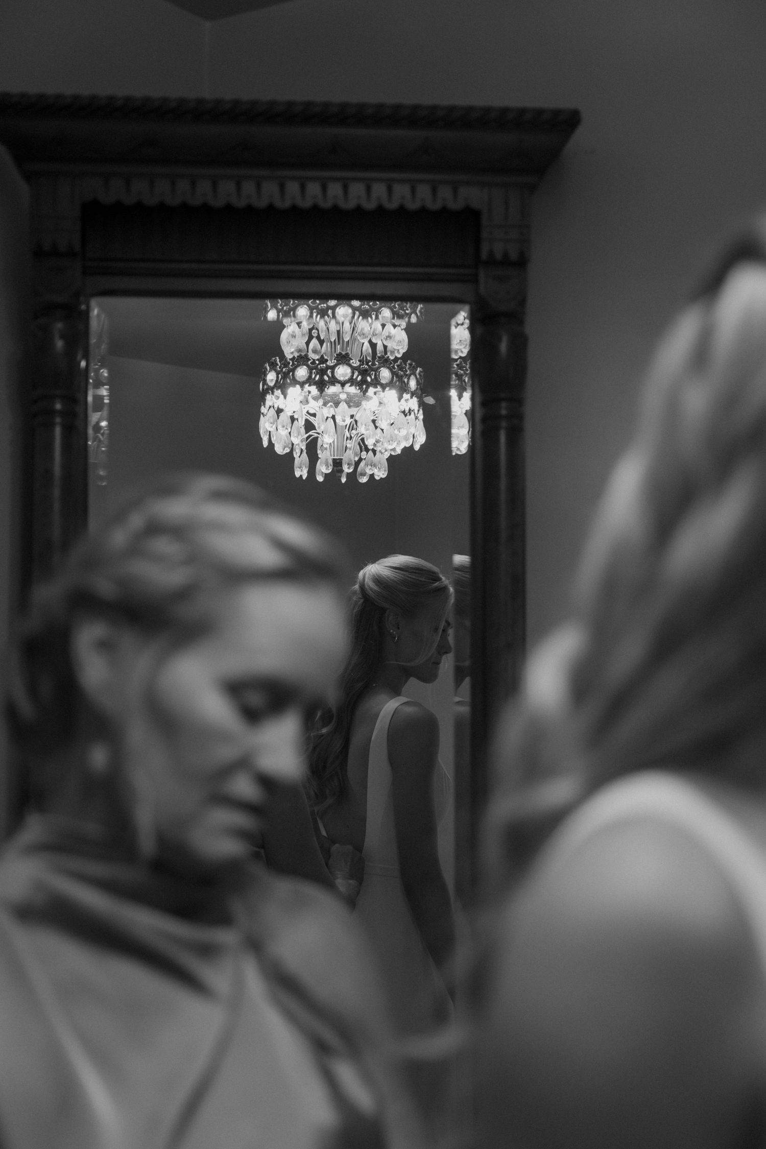 Crystal chandelier reflects in mirror during pre-wedding preparations.
