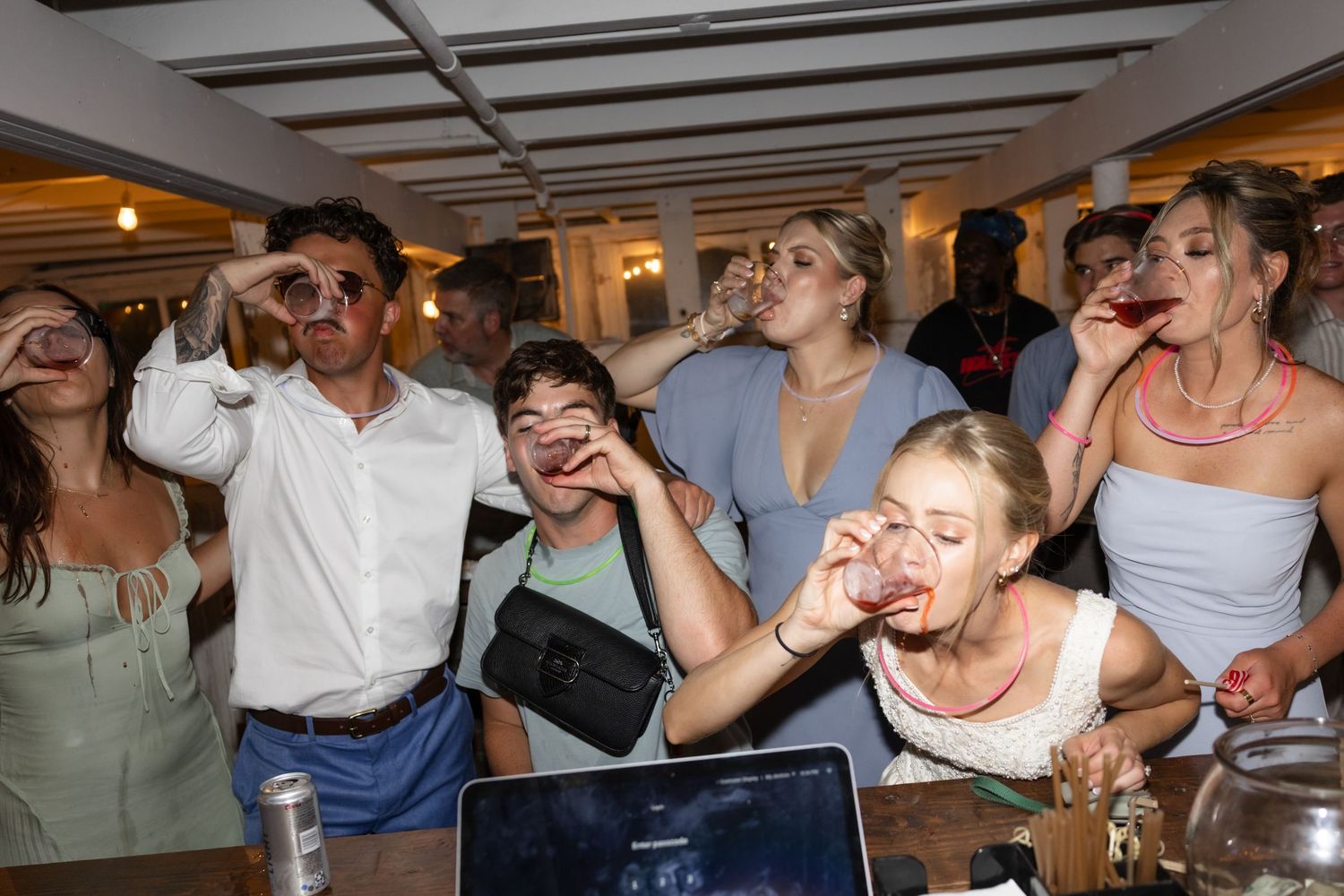 Party guests laughing and dancing in an indoor venue with exposed ceiling beams.