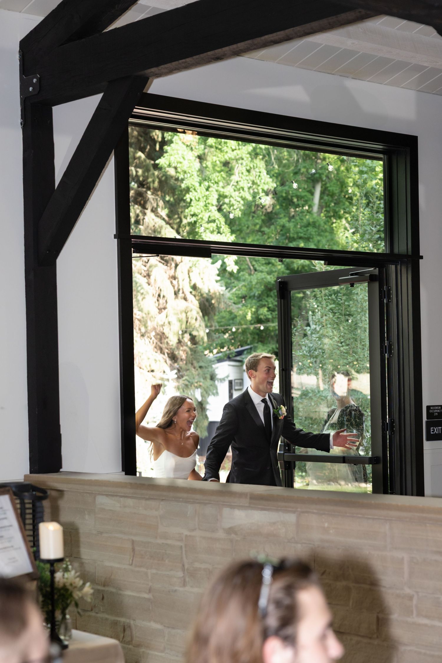 Wedding reception venue features modern white walls with large windows overlooking green landscape.