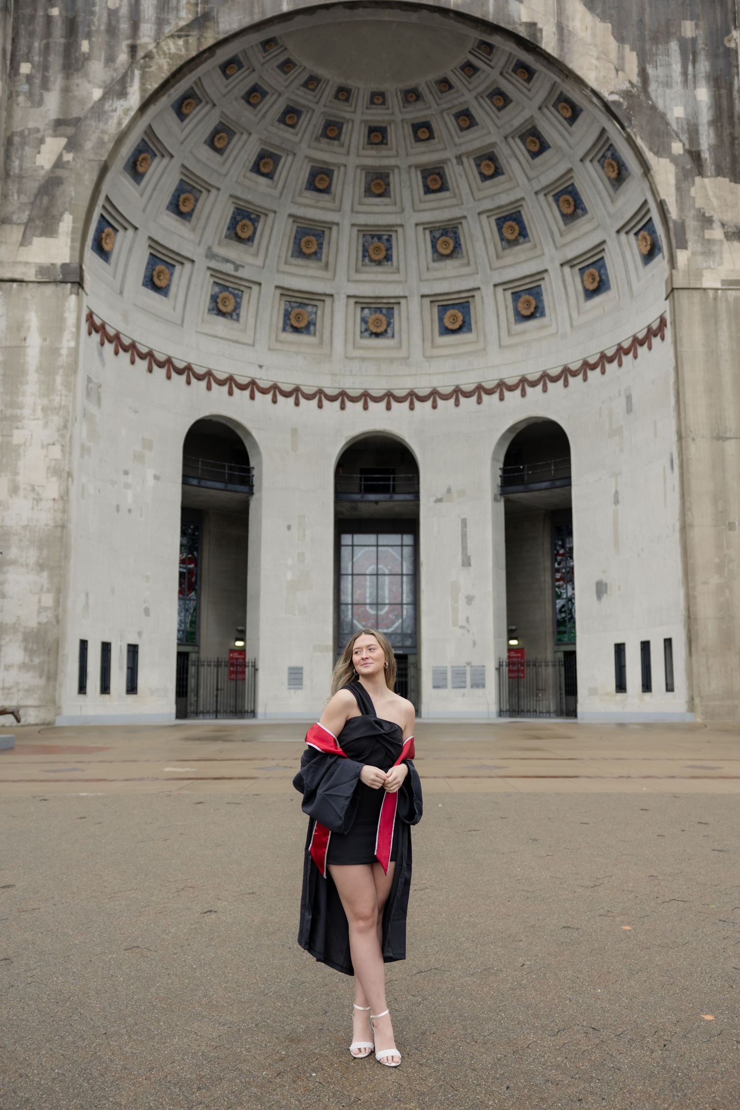 A graduation photo taken in front of a grand domed entrance with arched doorways.