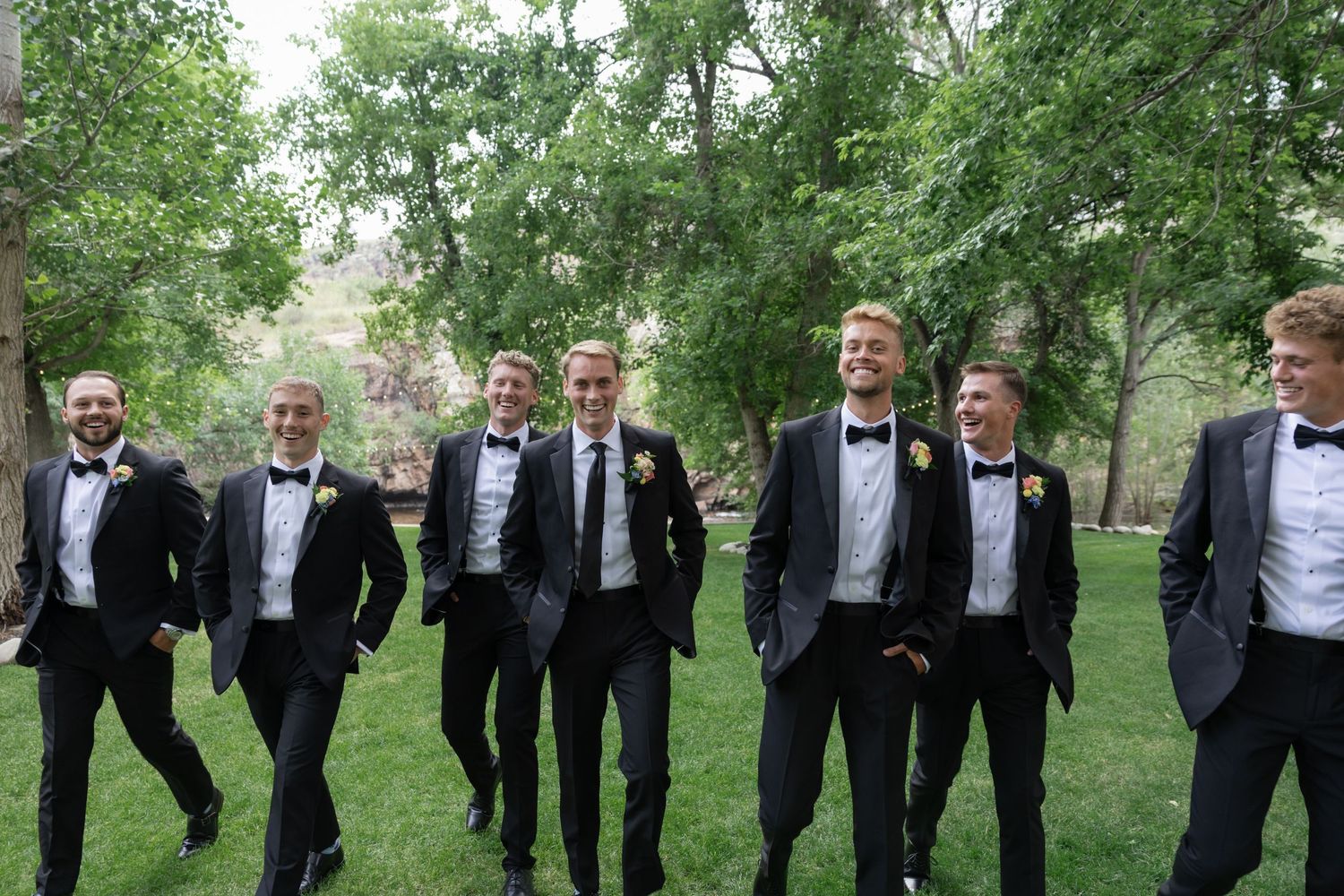 Black and white photo of groomsmen walking in formation wearing classic tuxedos.