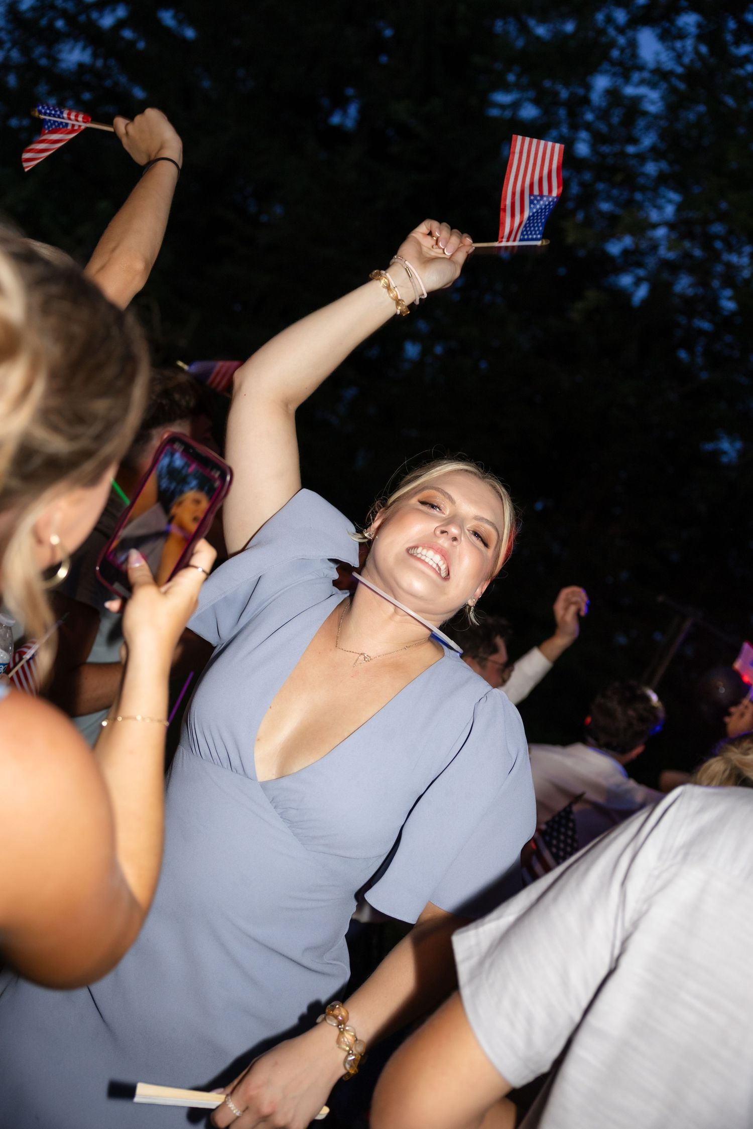 People dancing and celebrating with American flags at outdoor party.