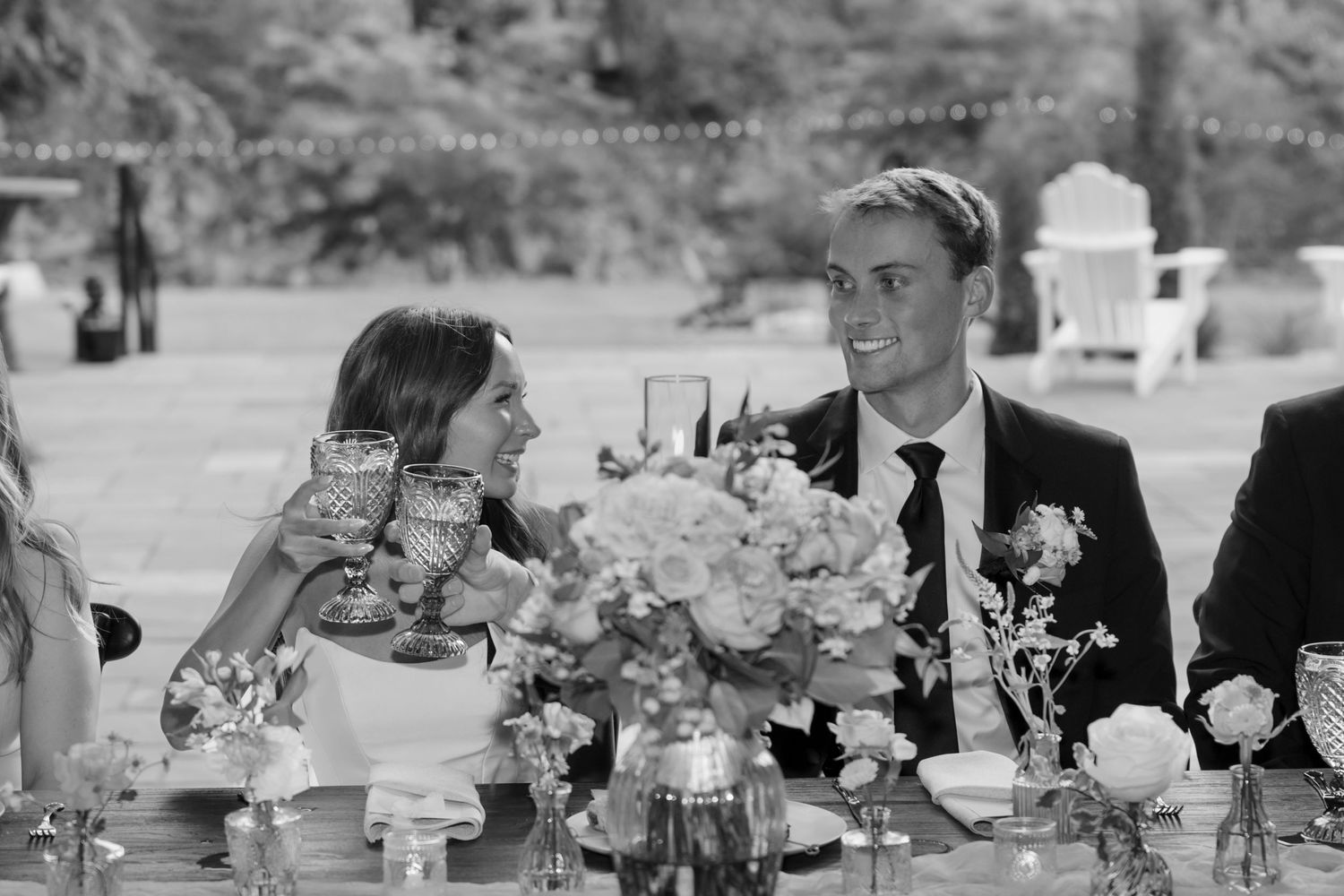 Black and white photo of wedding reception guests enjoying dinner at decorated tables.