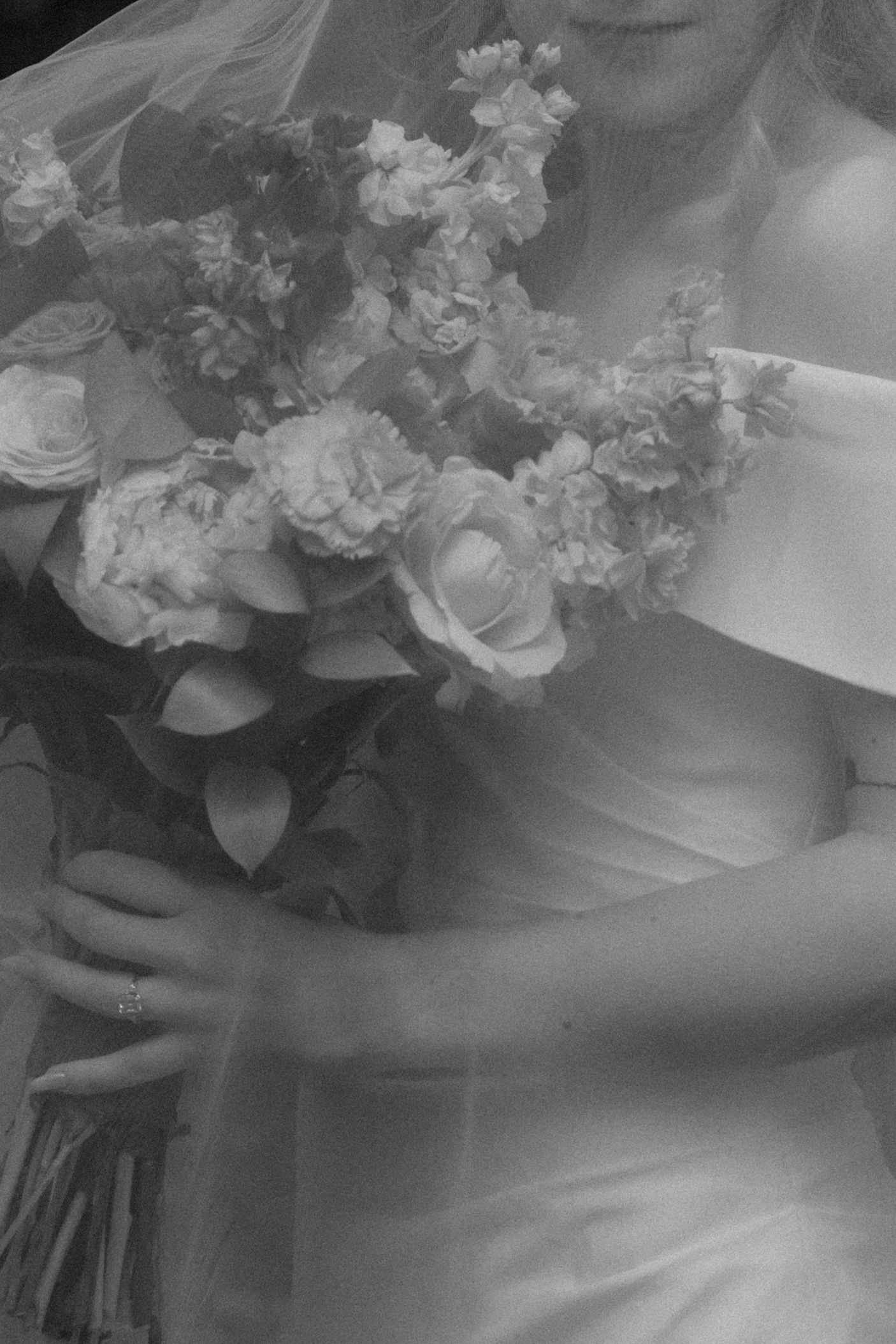 Detailed close-up of bridal bouquet with white roses and flowing dress fabric.