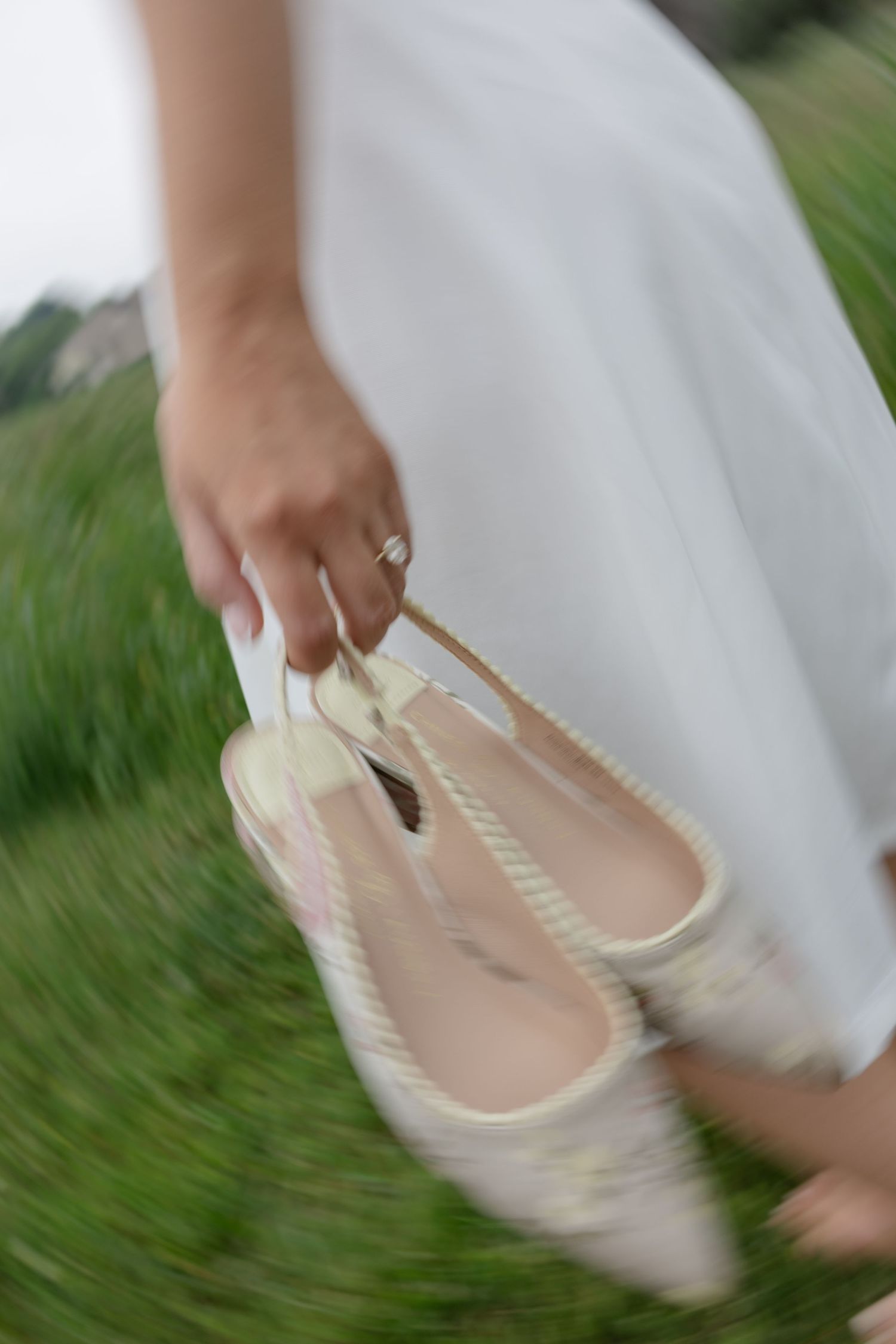 Cream colored ballet flats spin in motion against green grass.