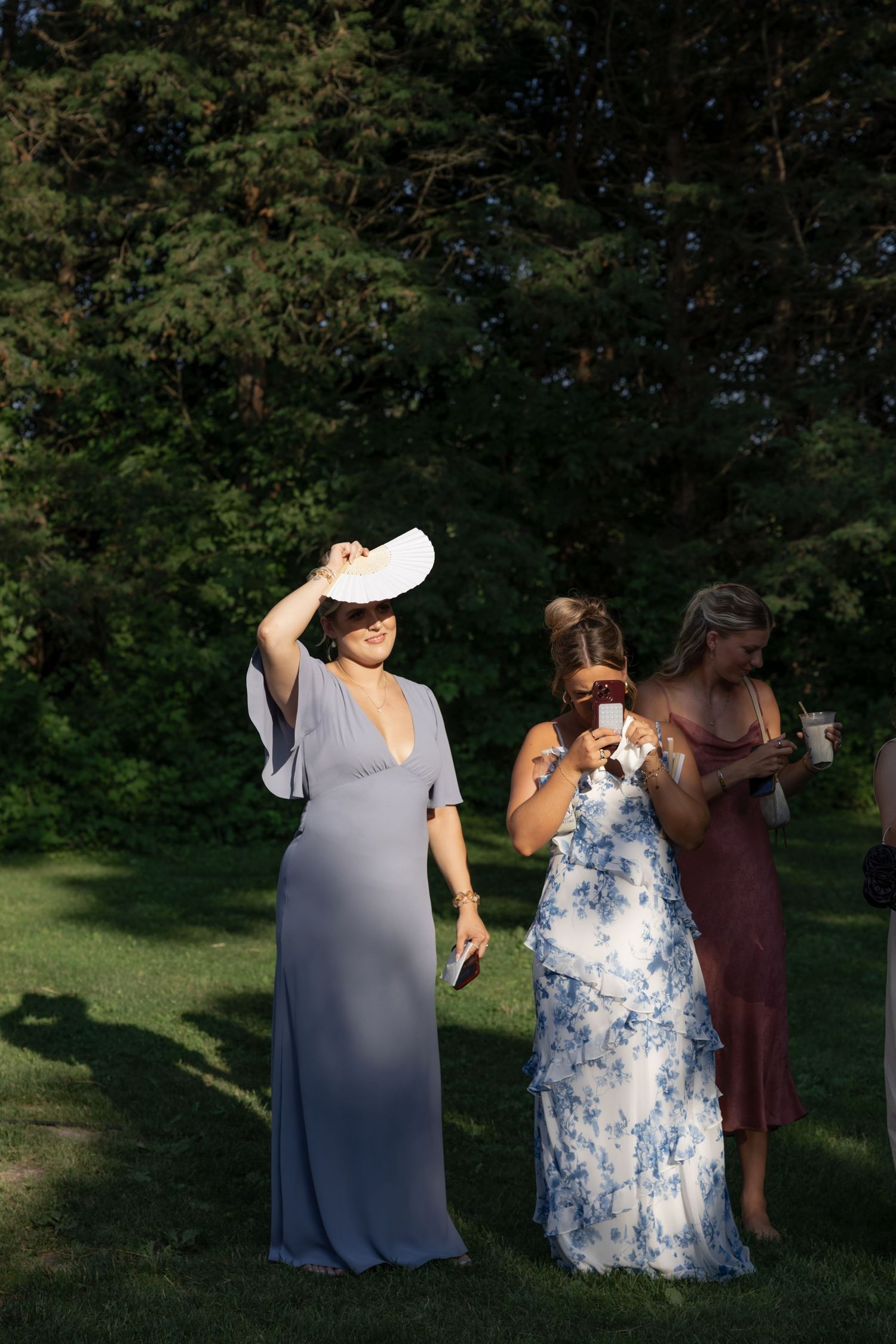 Wedding party members enjoying candid moments in a sunlit garden setting.