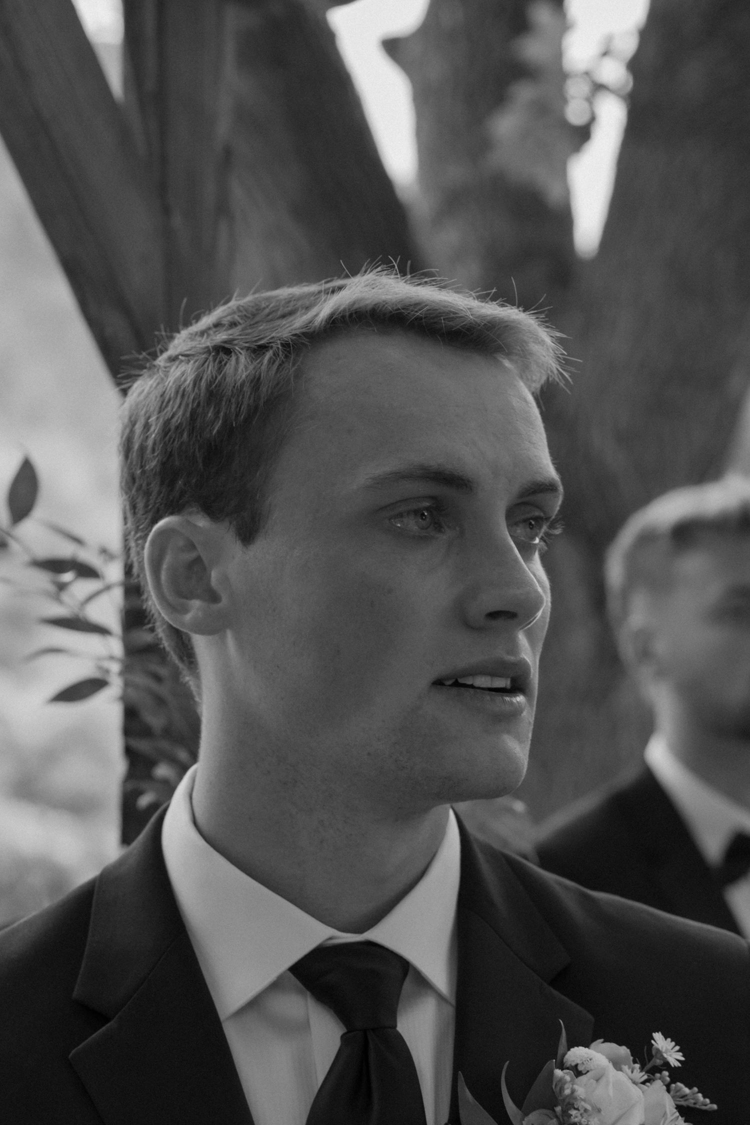Black and white portrait of groom wearing formal attire with boutonniere.
