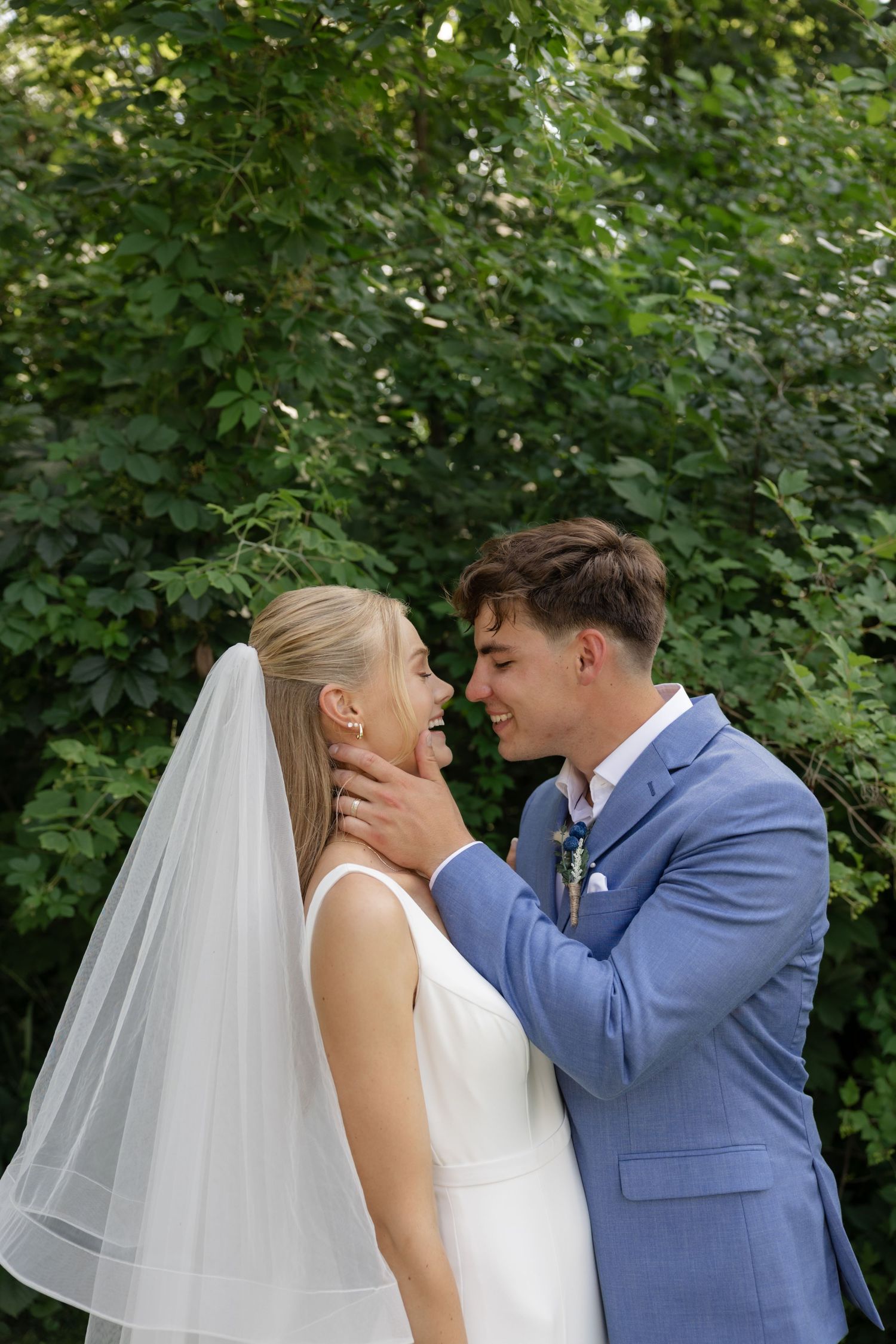 Romantic wedding portrait with couple embracing outdoors.