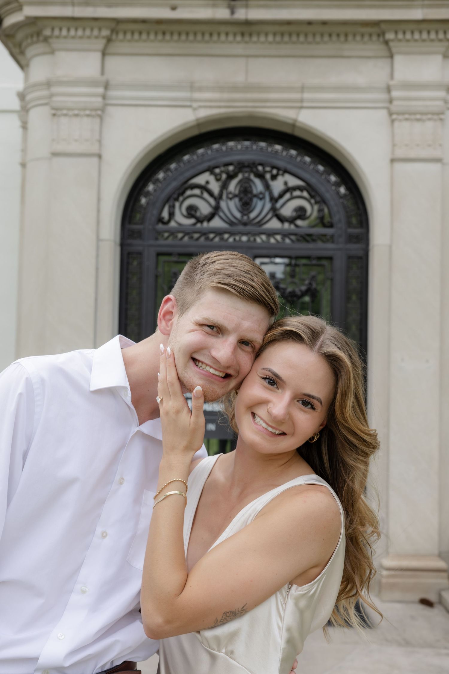 Elegant white mansion facade with ornate architectural details provides backdrop for romantic moment.