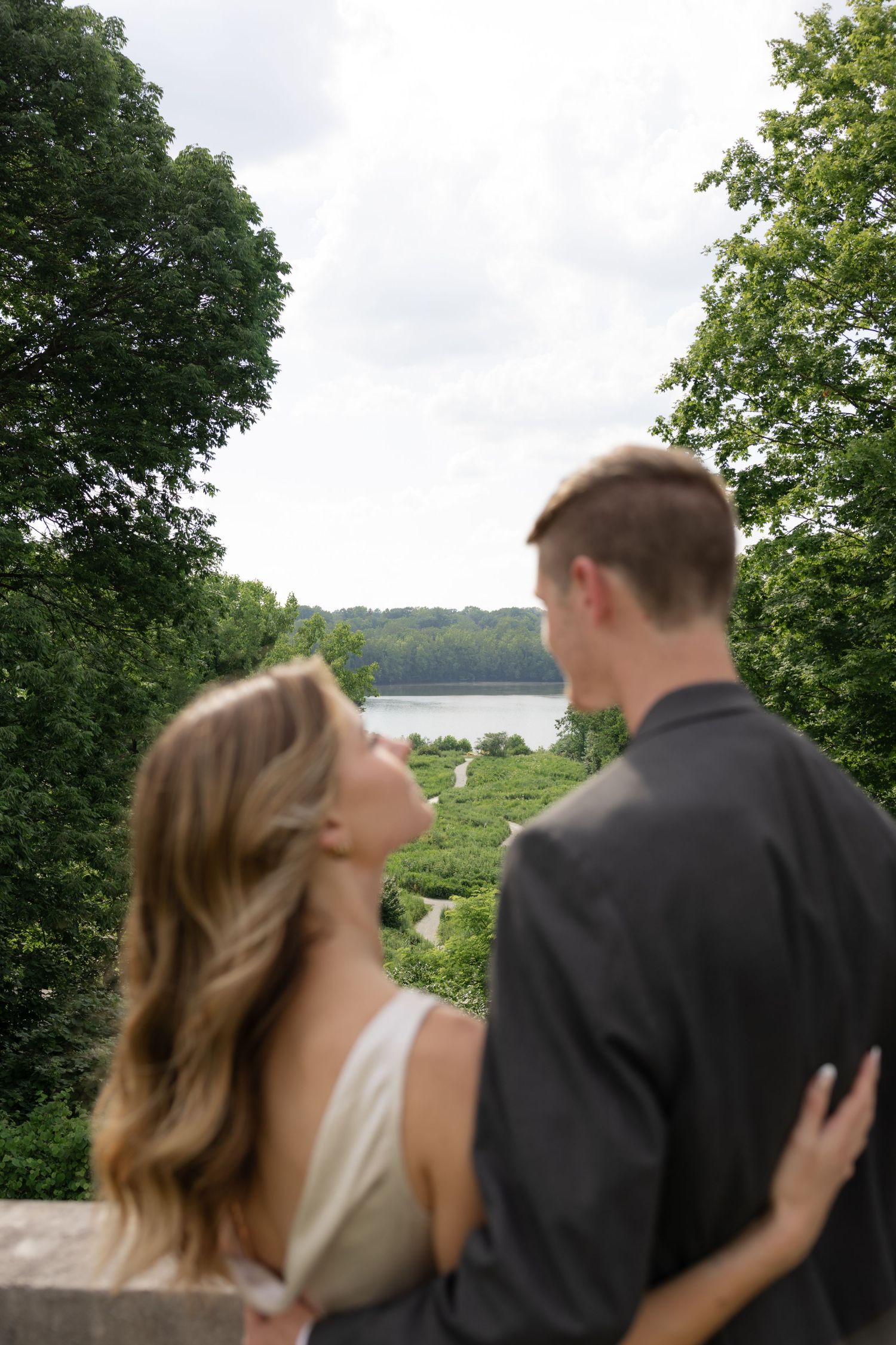 A couple shares a tender moment on a balcony overlooking a scenic lake view.