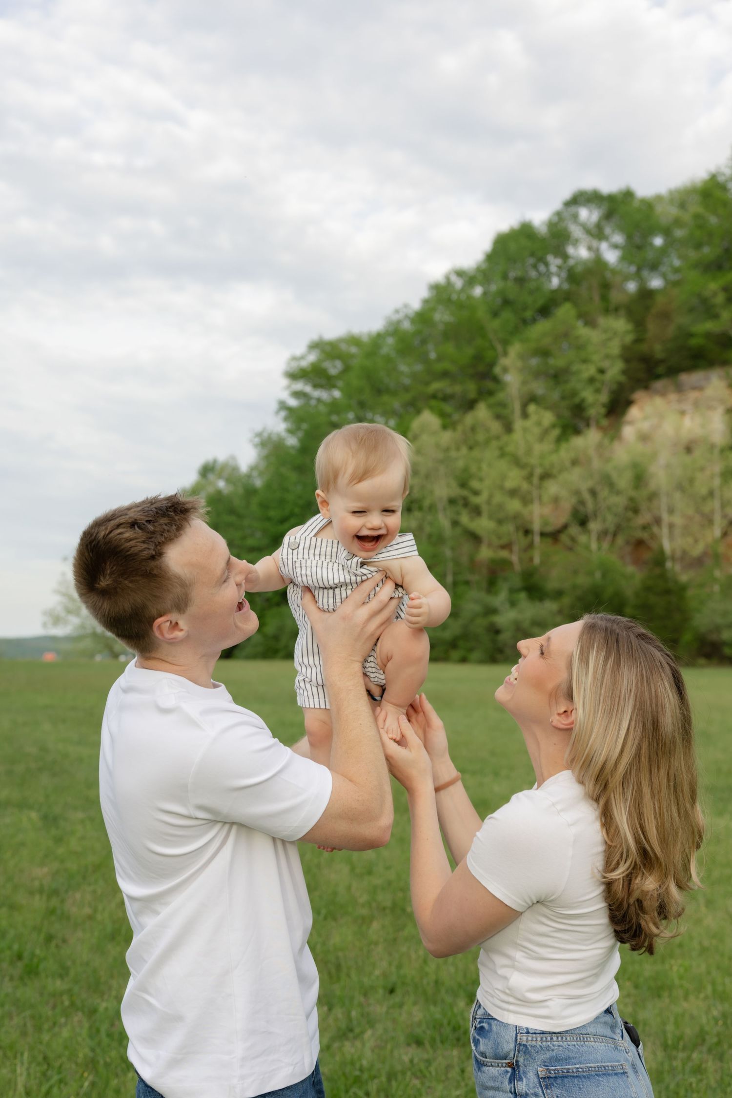Family sharing joyful moments together in an open field with trees in the background.