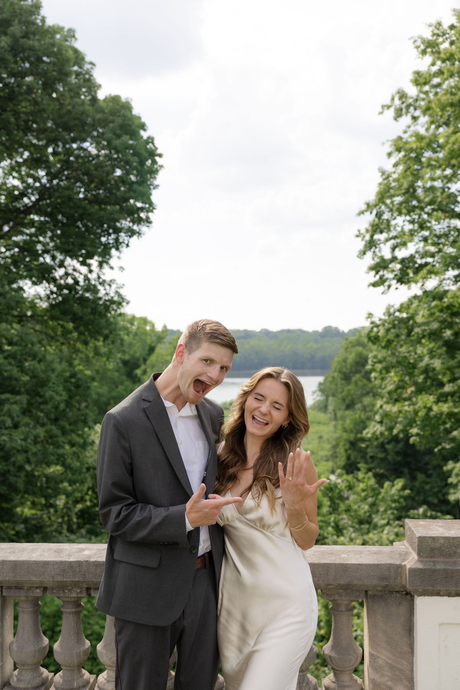 Pair enjoying a playful moment together on a stone balcony with trees in background.