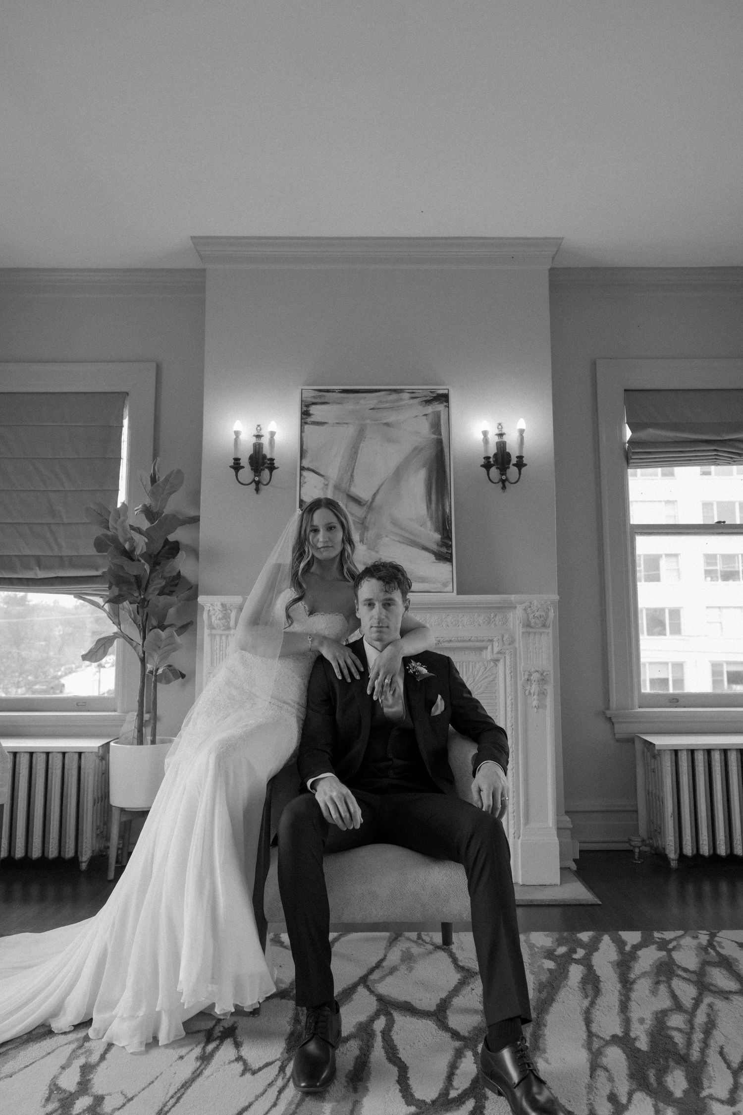 Elegant wedding portrait in formal room with fireplace and classic wall sconces.