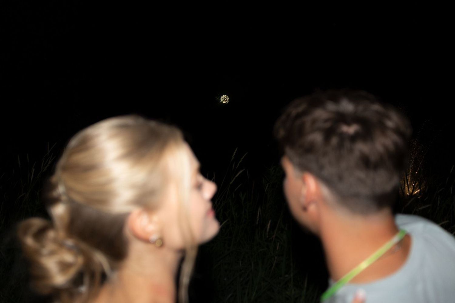 Partygoers dancing in a dimly lit outdoor setting with string lights overhead.
