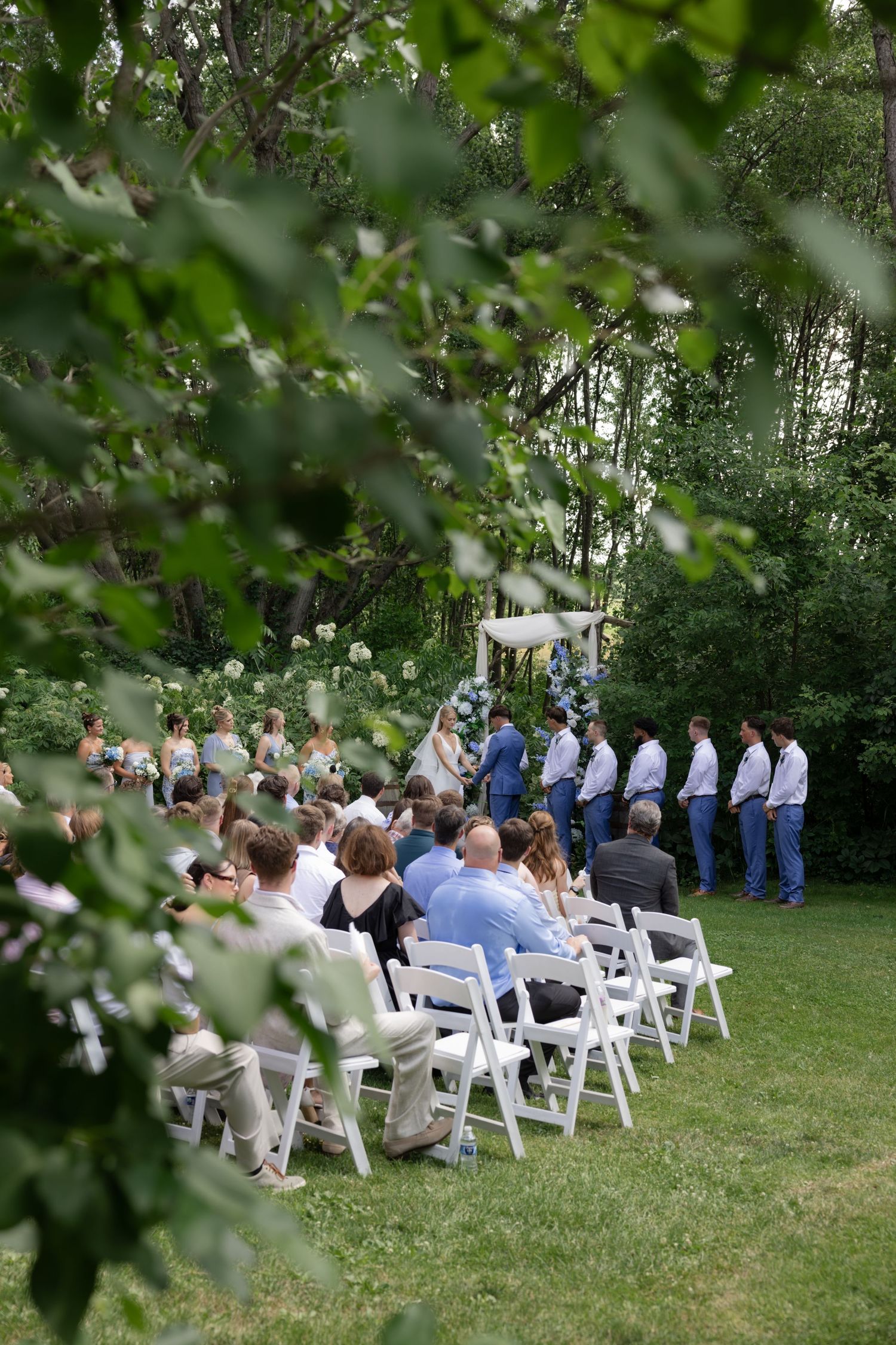 Scenic view of wedding guests seated for an outdoor ceremony surrounded by lush greenery.