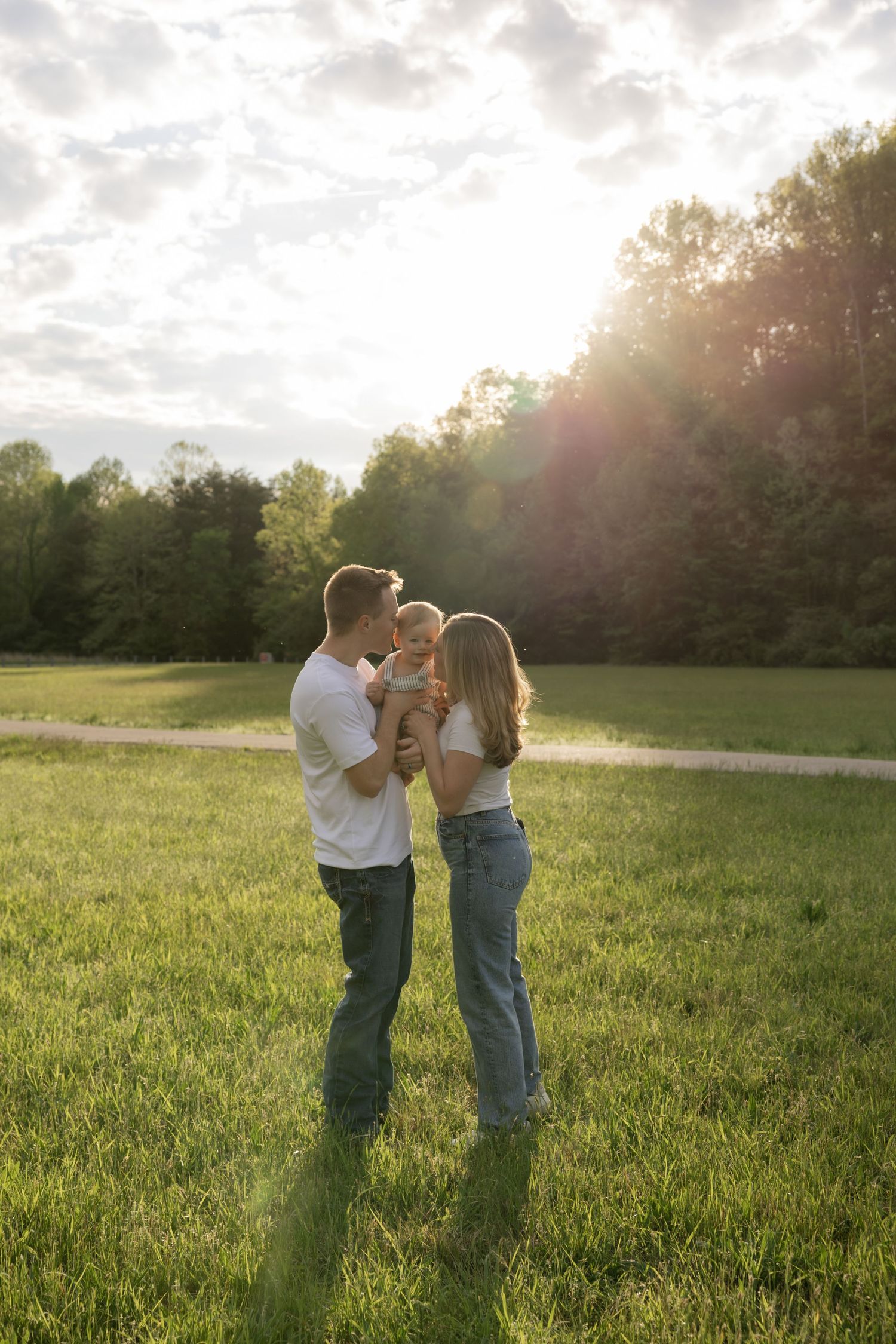 Family portrait in golden sunset light with trees and grass in the background.