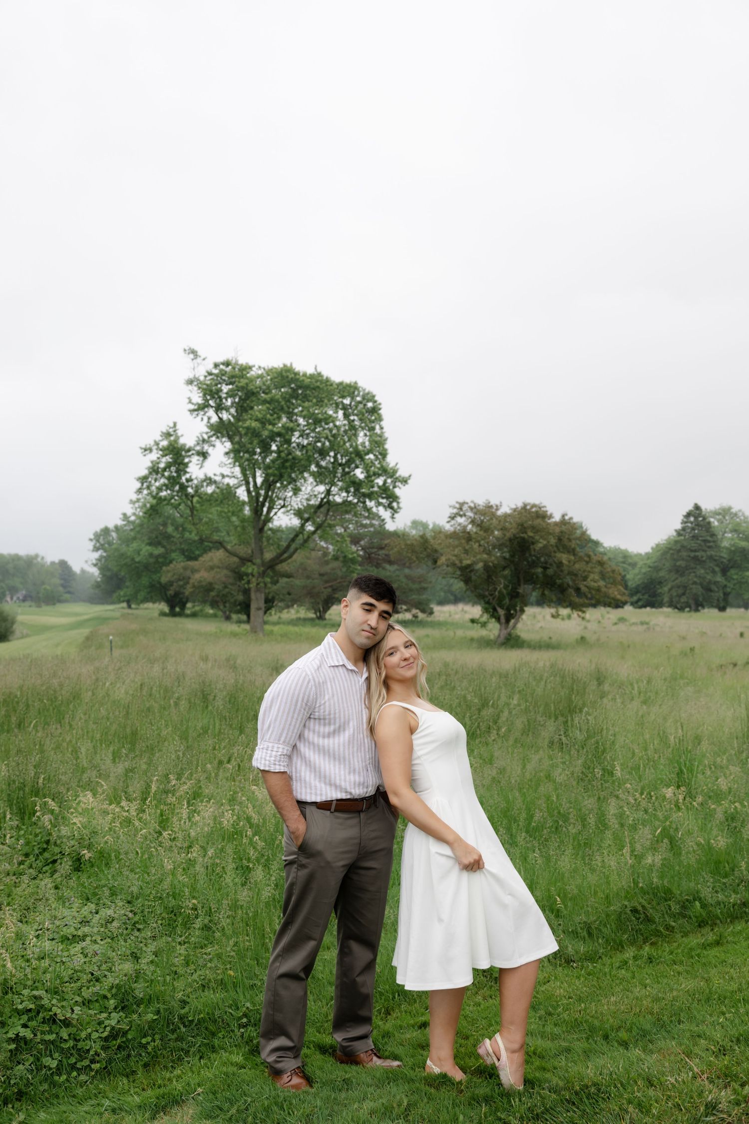 A couple shares a playful moment in a rustic countryside setting.