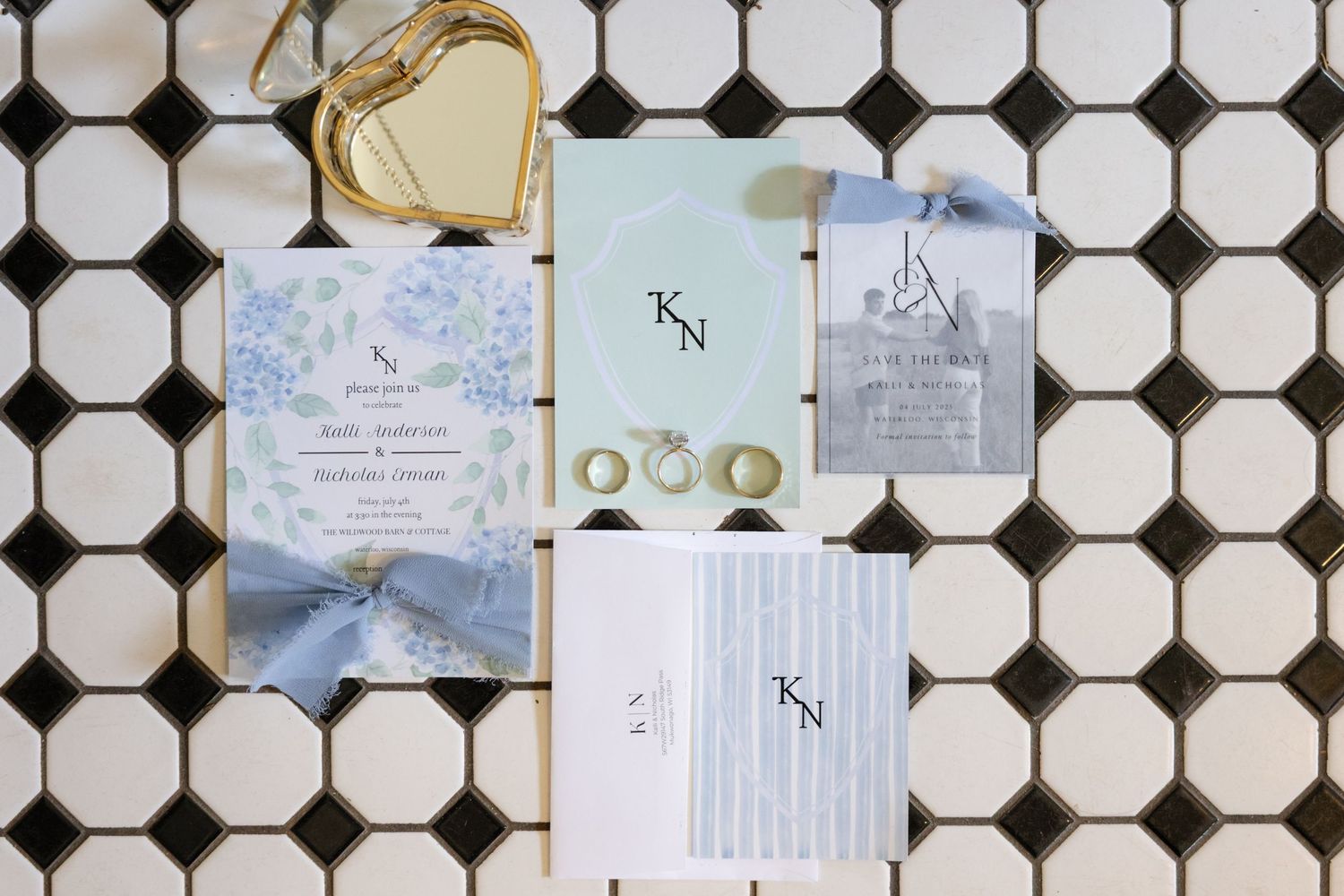 Wedding invitation suite with blue ribbons and gold details on geometric tile background.