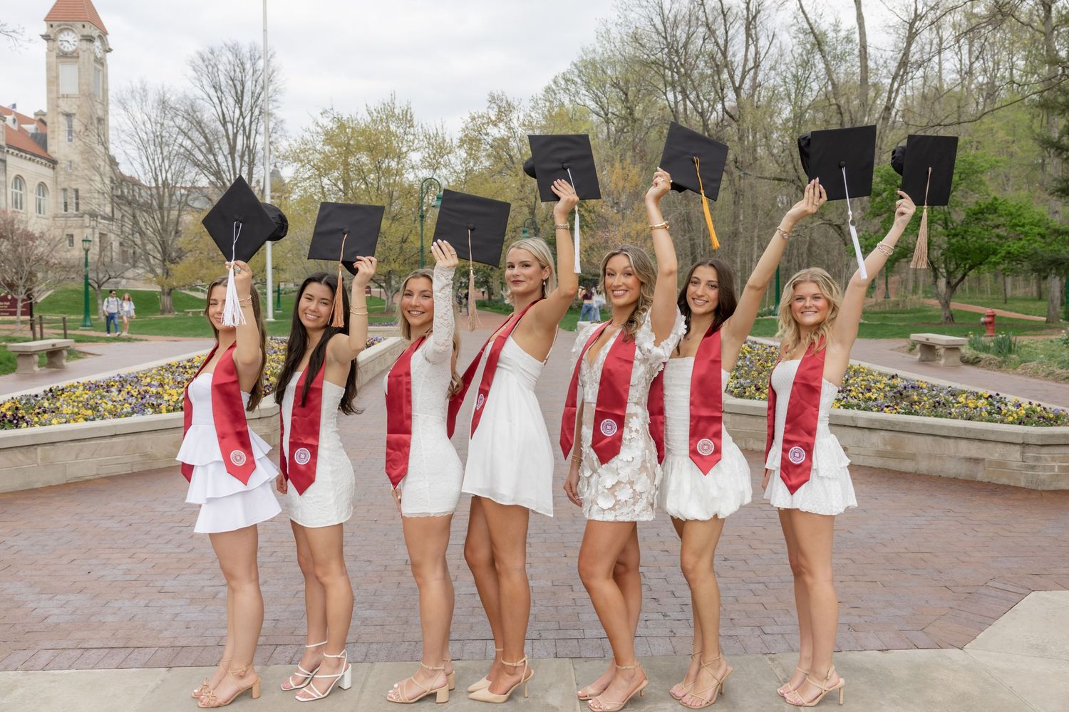 Graduation celebration photo with traditional caps being tossed in the air on campus grounds.