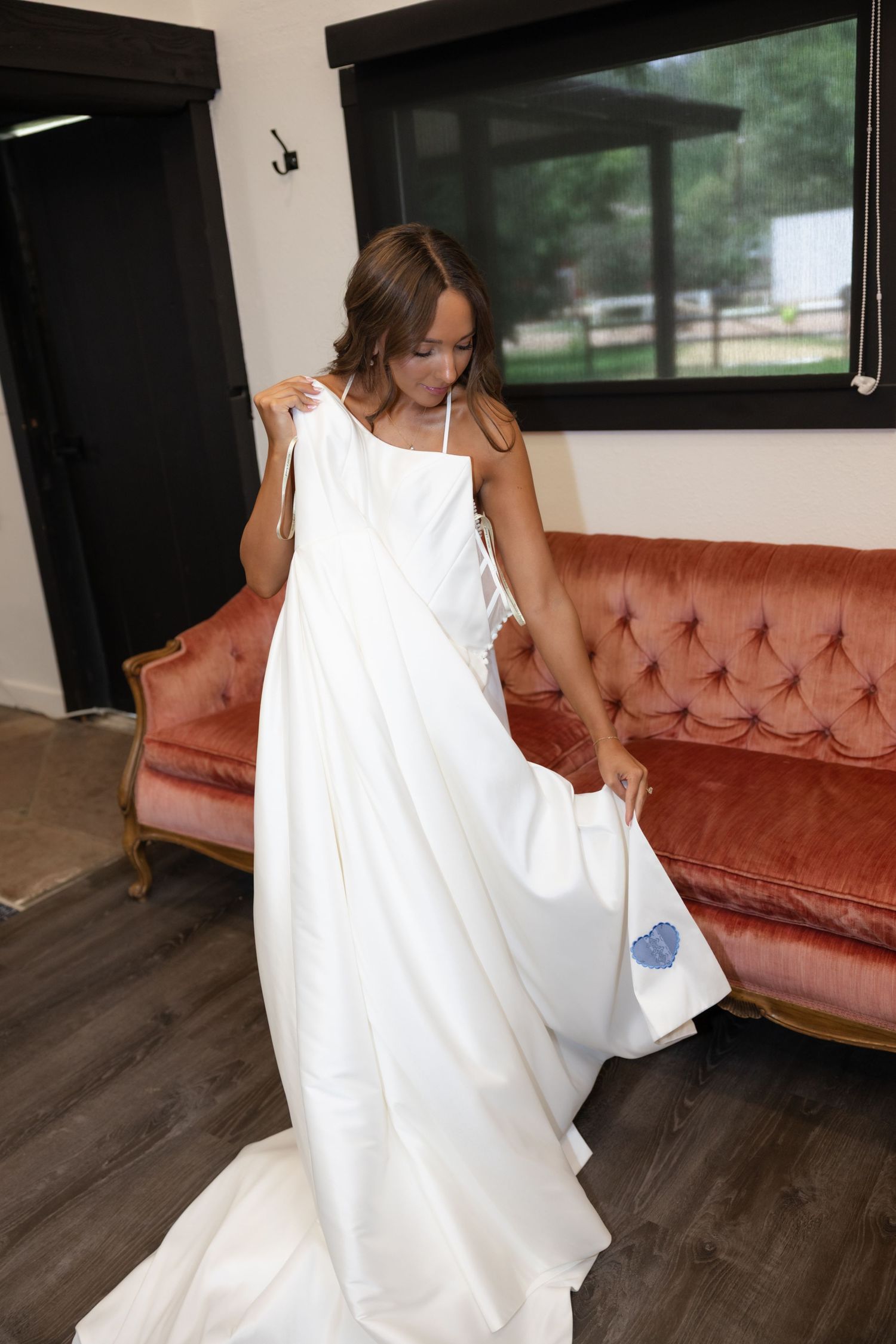 White dress flowing in movement against vintage pink couch indoors.