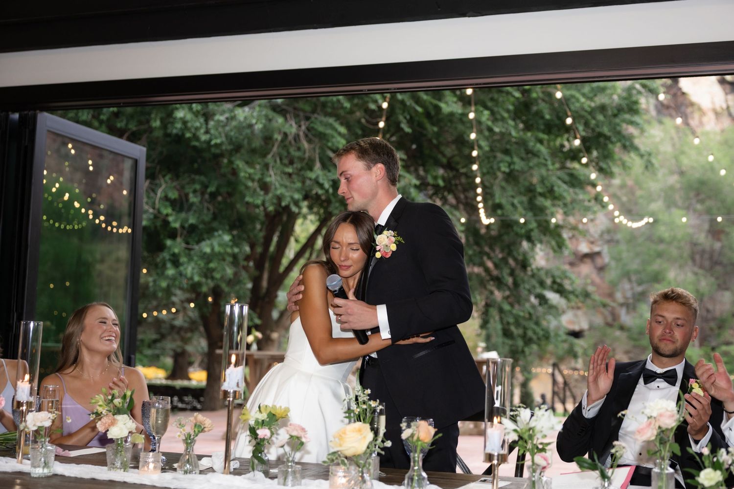 Wedding reception dining area set against natural greenery and soft lighting.