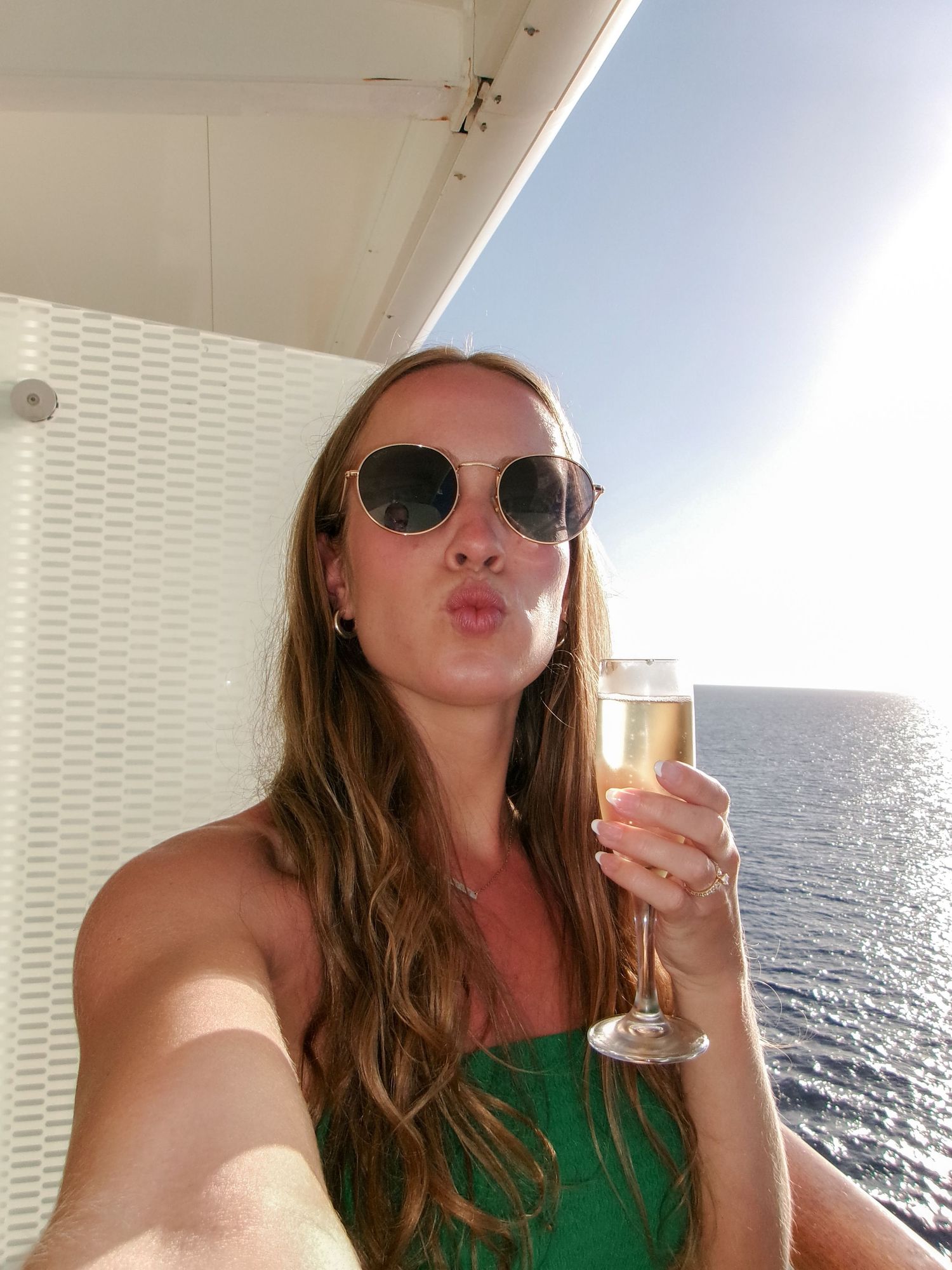 Fun selfies on a cruise ship balcony with ocean views and champagne glasses.