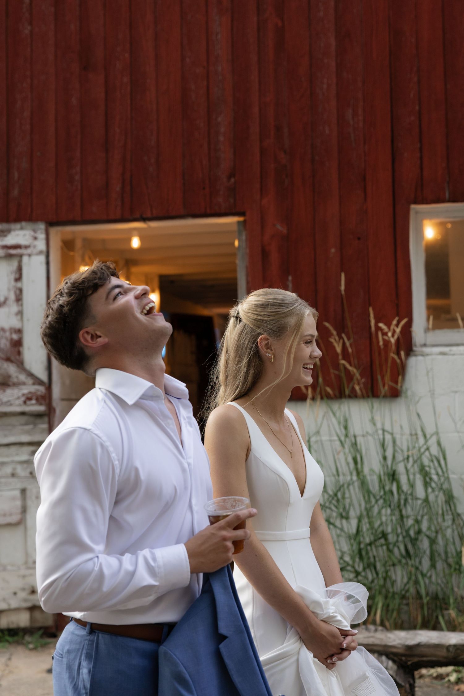 Couple sharing a joyful moment together against a rustic red barn backdrop.