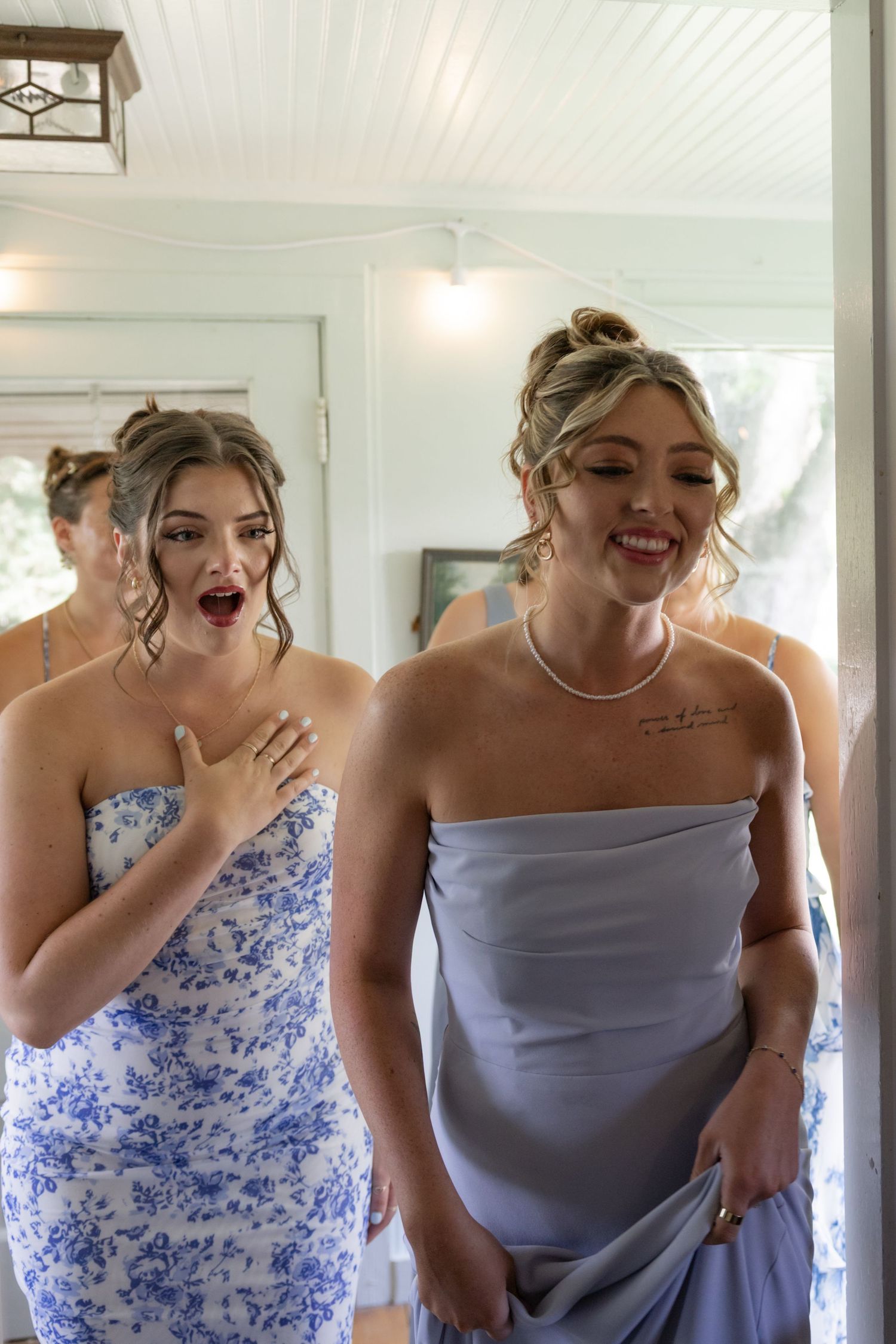 Bridesmaids in blue floral and solid dresses share laughter during pre-wedding preparations.